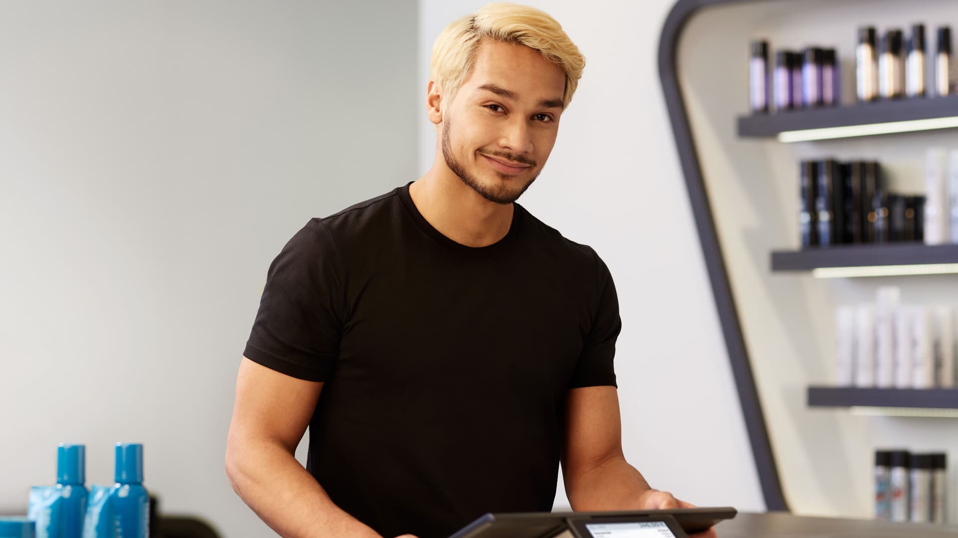 Ein Friseur steht in einem Friseursalon an der Kasse.