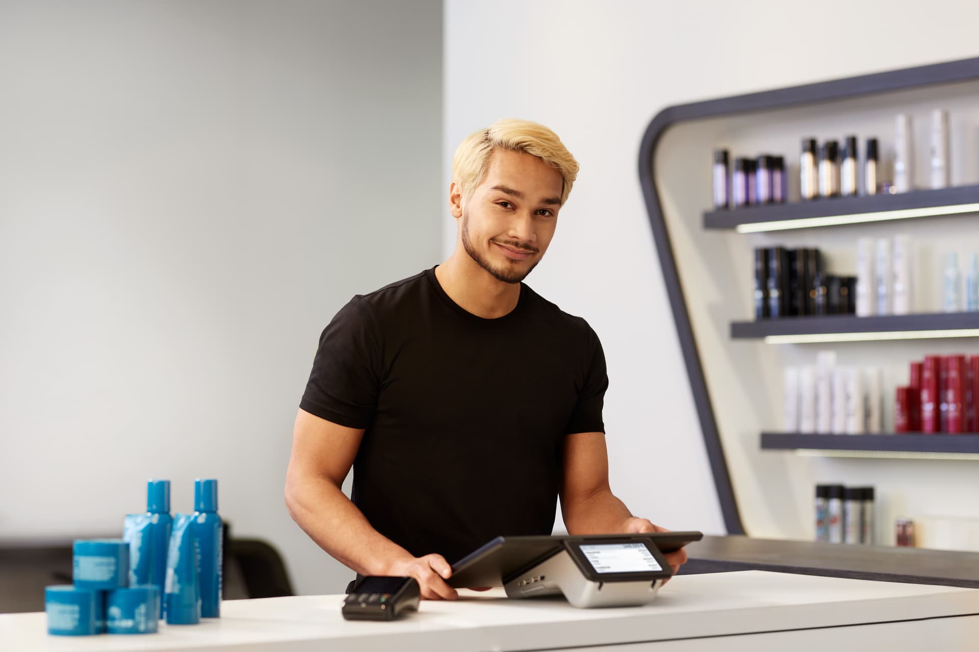 Ein Friseur steht in einem Friseursalon an der Kasse.