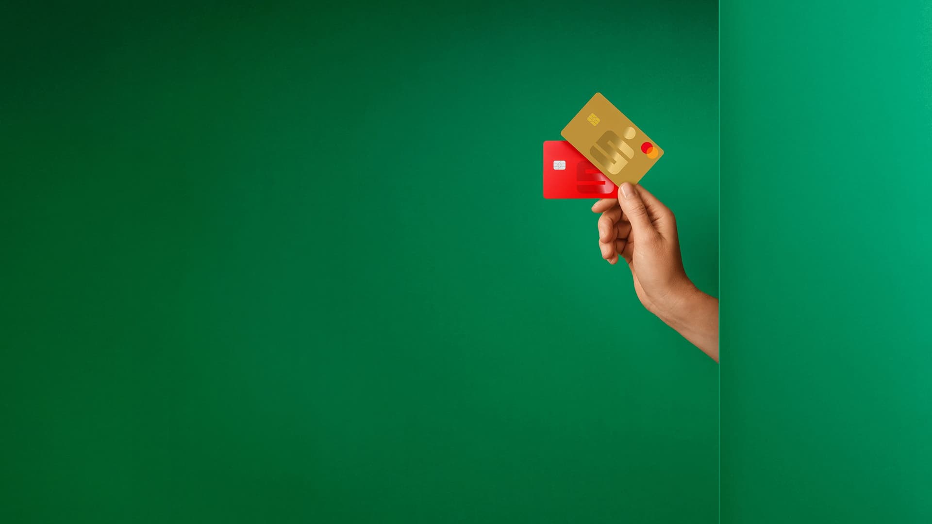 Hand hält eine rote und eine goldene Sparkassen-Debitkarte vor grünem Hintergrund.