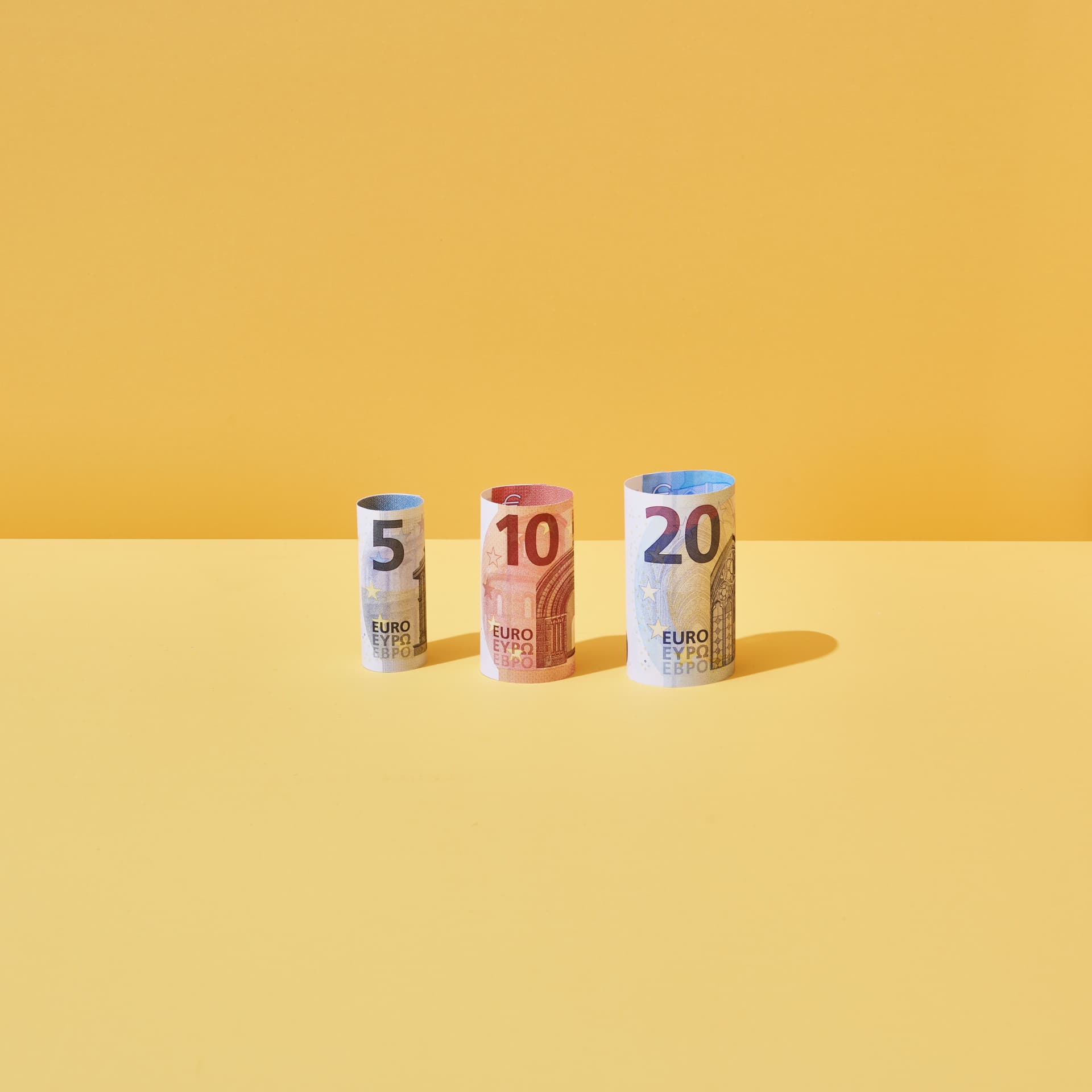 Farbige kuenstlerische Bilder die Geld darstellen. Hintergrund rot, gelb, orange oder gruen. Darstellung von Münzrollen, Geldscheinen und Münzen