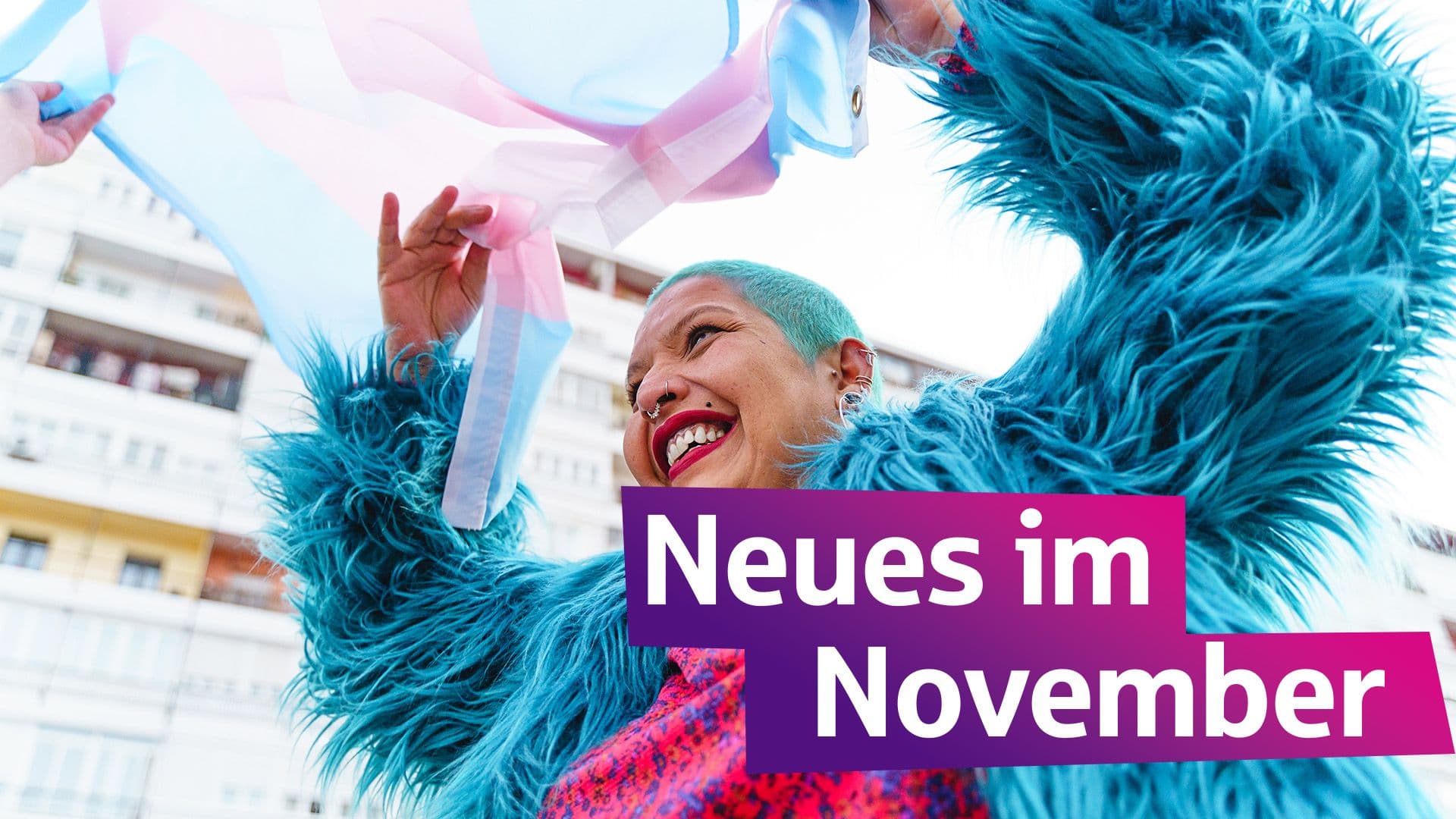 Eine Frau mit flauschiger Jacke und türkisfarbenen Haaren freut sich. Sie schwenkt eine bisexuelle Flagge.