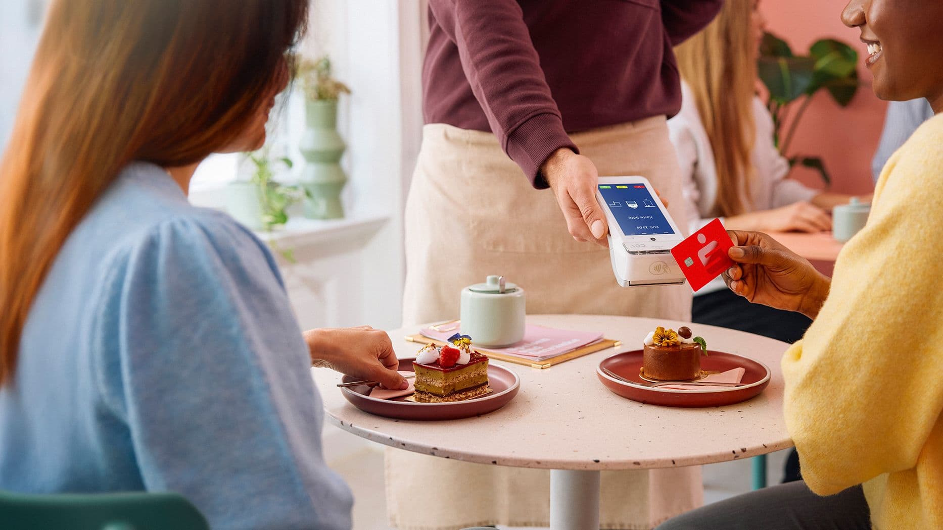 Person bezahlt mit Sparkassen-Card kontaktlos am Kartenlesegerät im Café