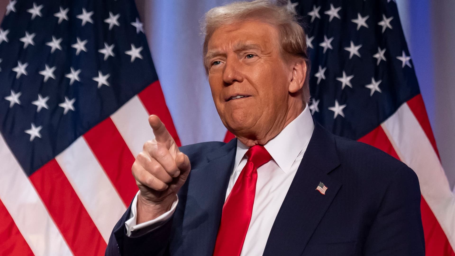 Donald Trump steht vor amerikanischen Flaggen. Er zeigt mit dem Finger Richtung Kamera.