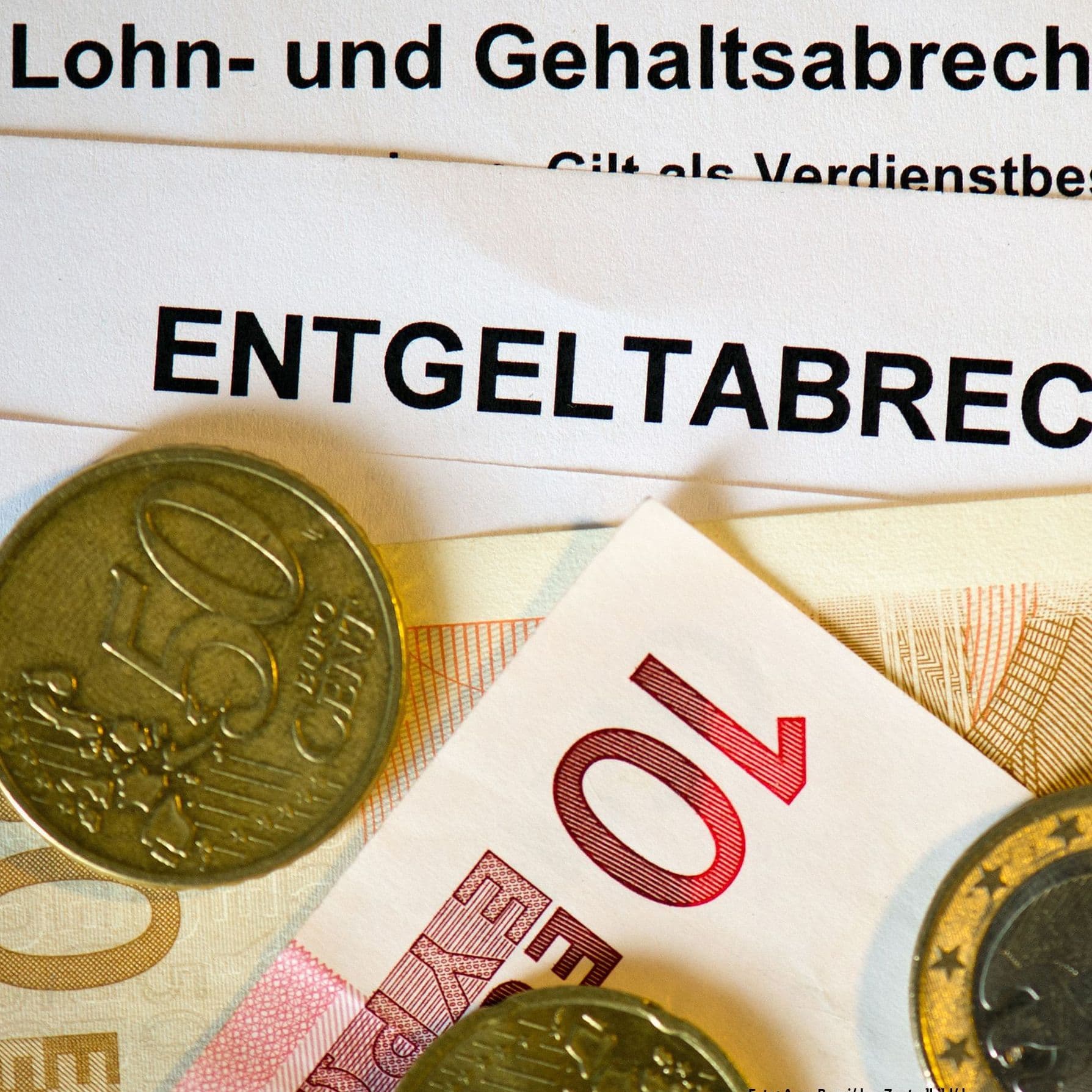 Gehaltsabrechnung mit einigen Münzen und Geldscheinen darauf