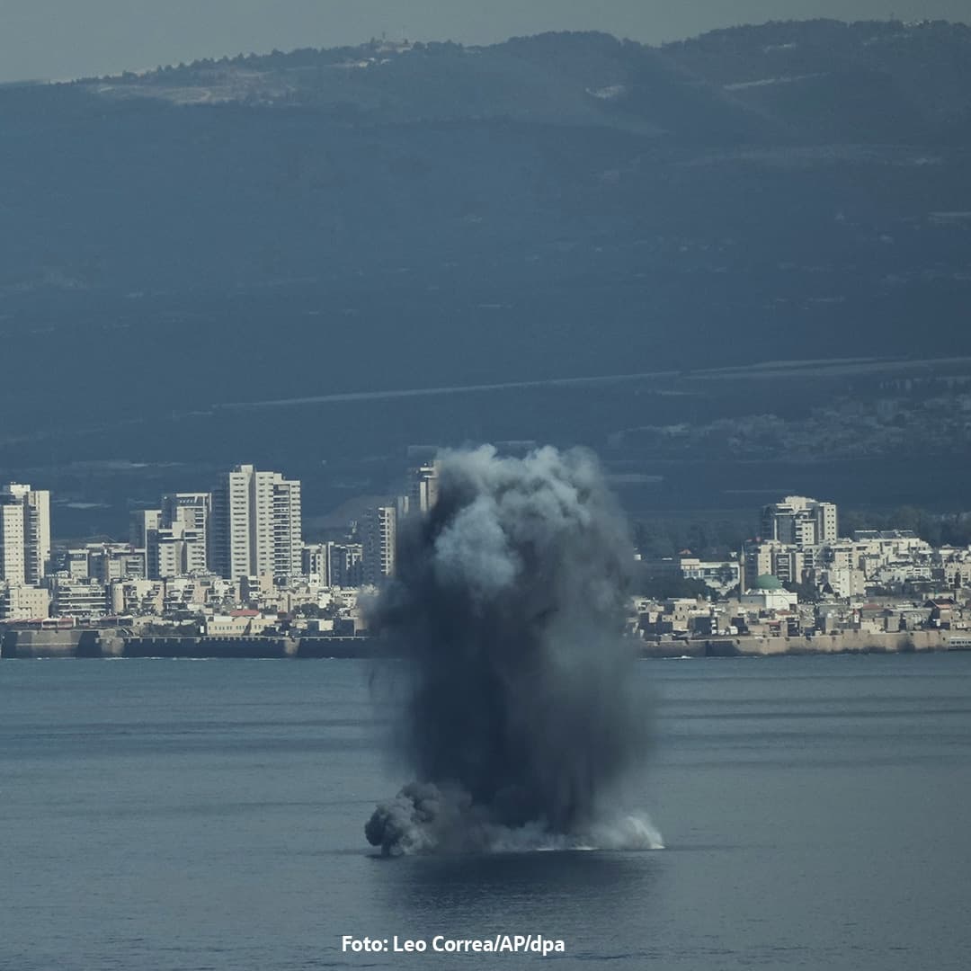 Große schwarze Rauch- und Wassersäule steigt nach Explosion vor einer Küstenstadt auf.