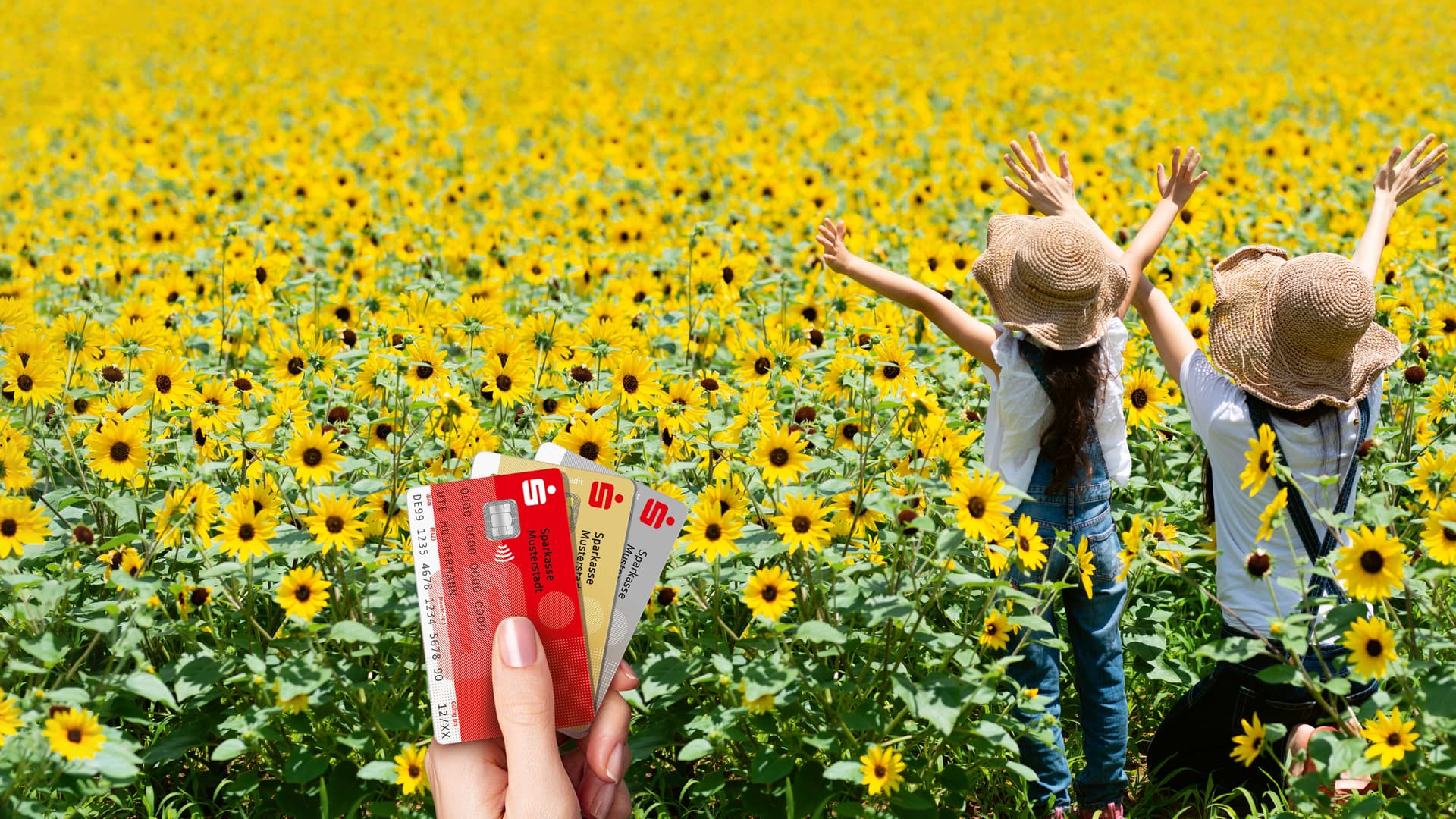 Zwei Kinder mit Strohhüten stehen fröhlich in einem weitläufigen Sonnenblumenfeld. Im Vordergrund hält eine Hand drei Sparkassen-Karten hoch – eine Sparkassen-Card (Debitkarte), eine Kreditkarte und eine goldene Kreditkarte.