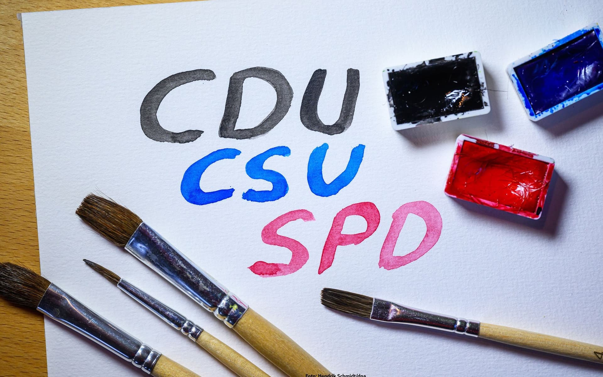 Auf einem weißen Papier stehen CDU,CSU und SPD. Sie sind mit Aquarellfarben aufgemalt.