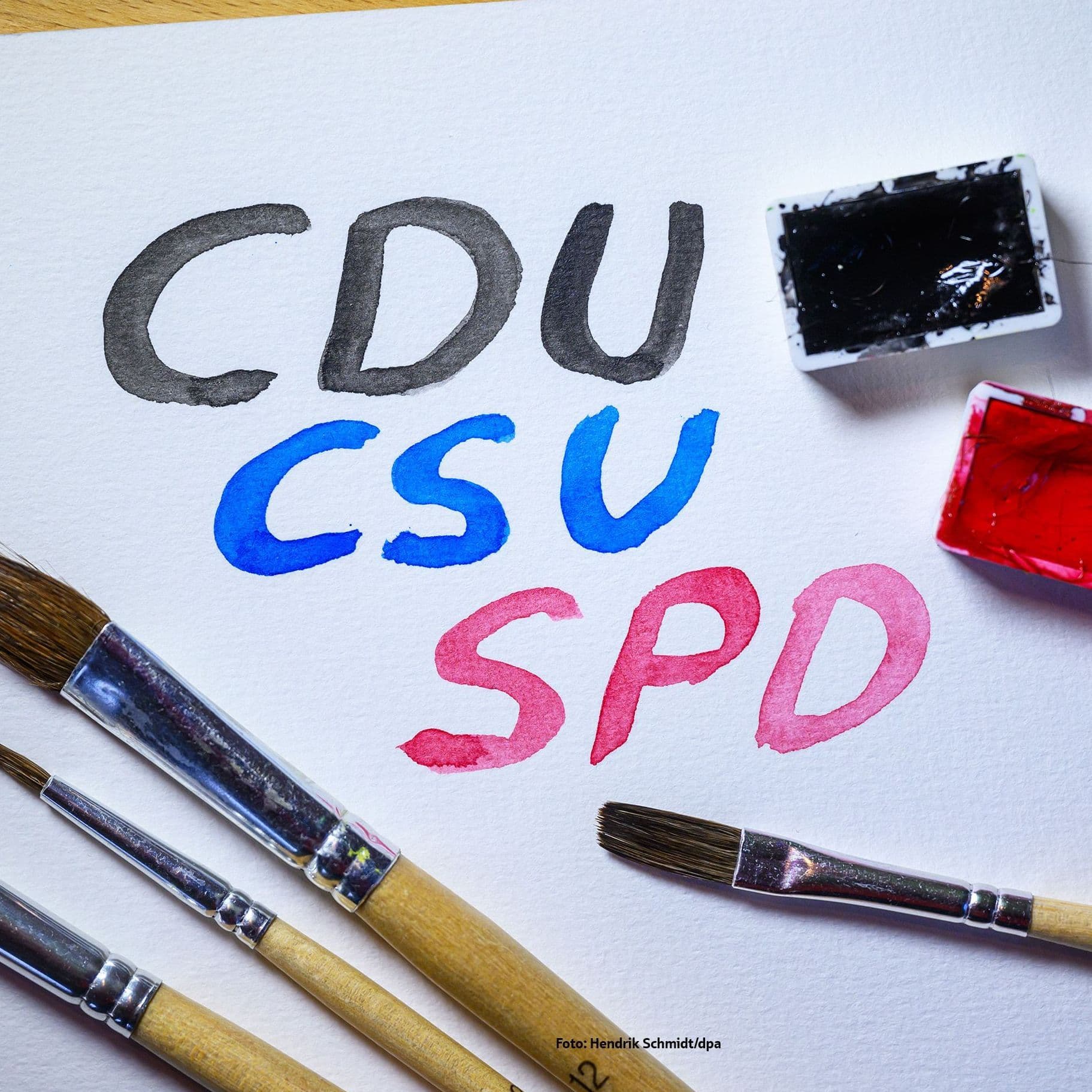 Auf einem weißen Papier stehen CDU,CSU und SPD. Sie sind mit Aquarellfarben aufgemalt.