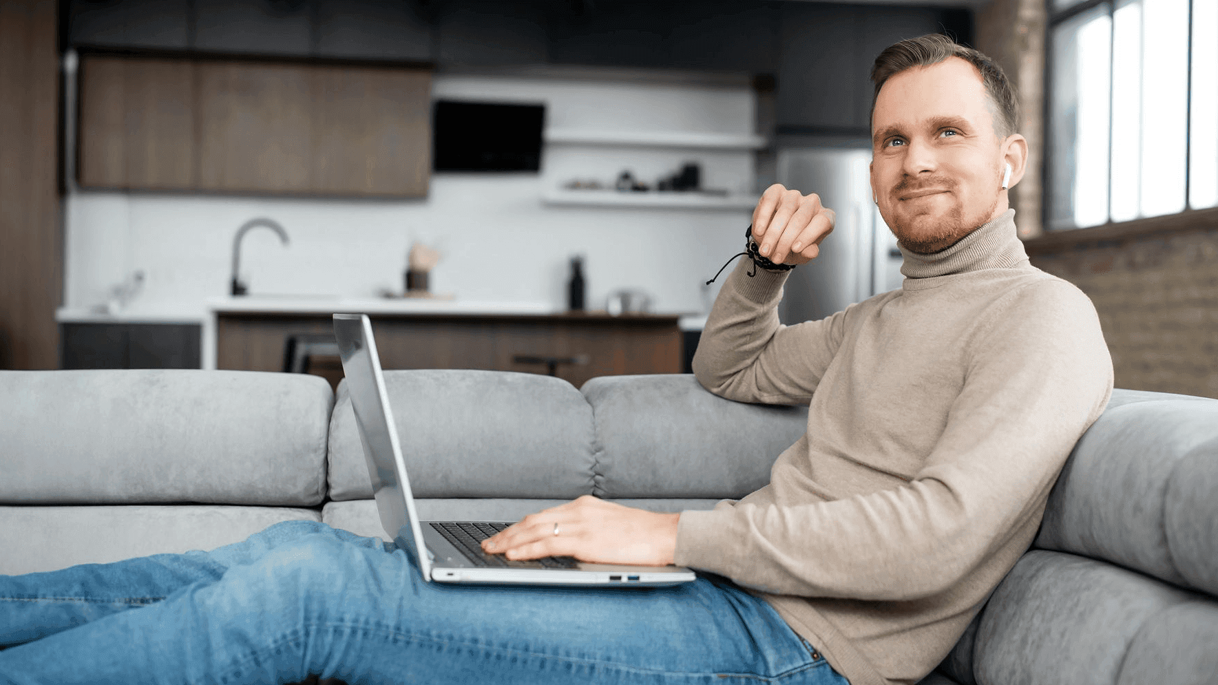Ein Mann sitzt mit seinem Laptop auf dem Sofa.