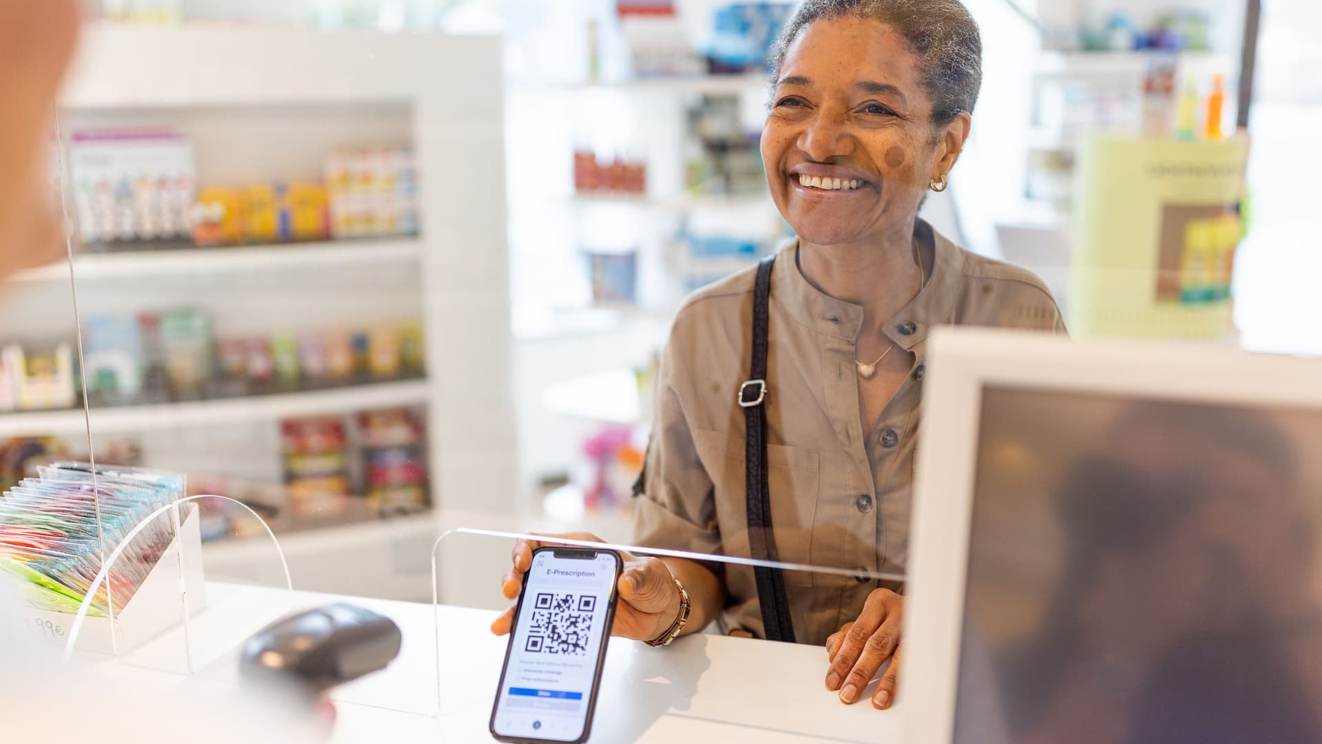 Eine aeltere POC zeigt ihr Handy in einer Apotheke.