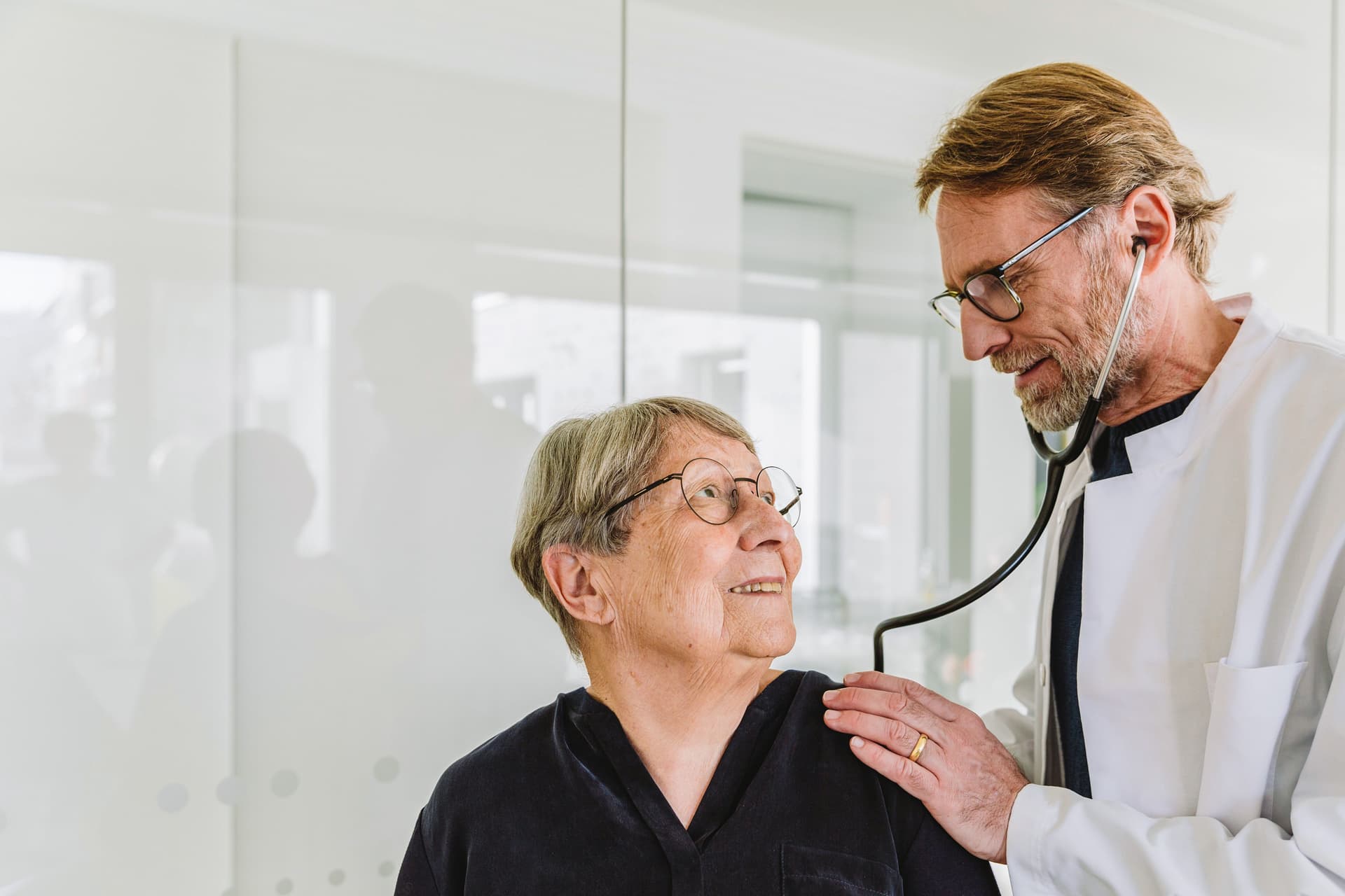 Ein Arzt untersucht eine ältere Patientin mit einem Stethoskop.