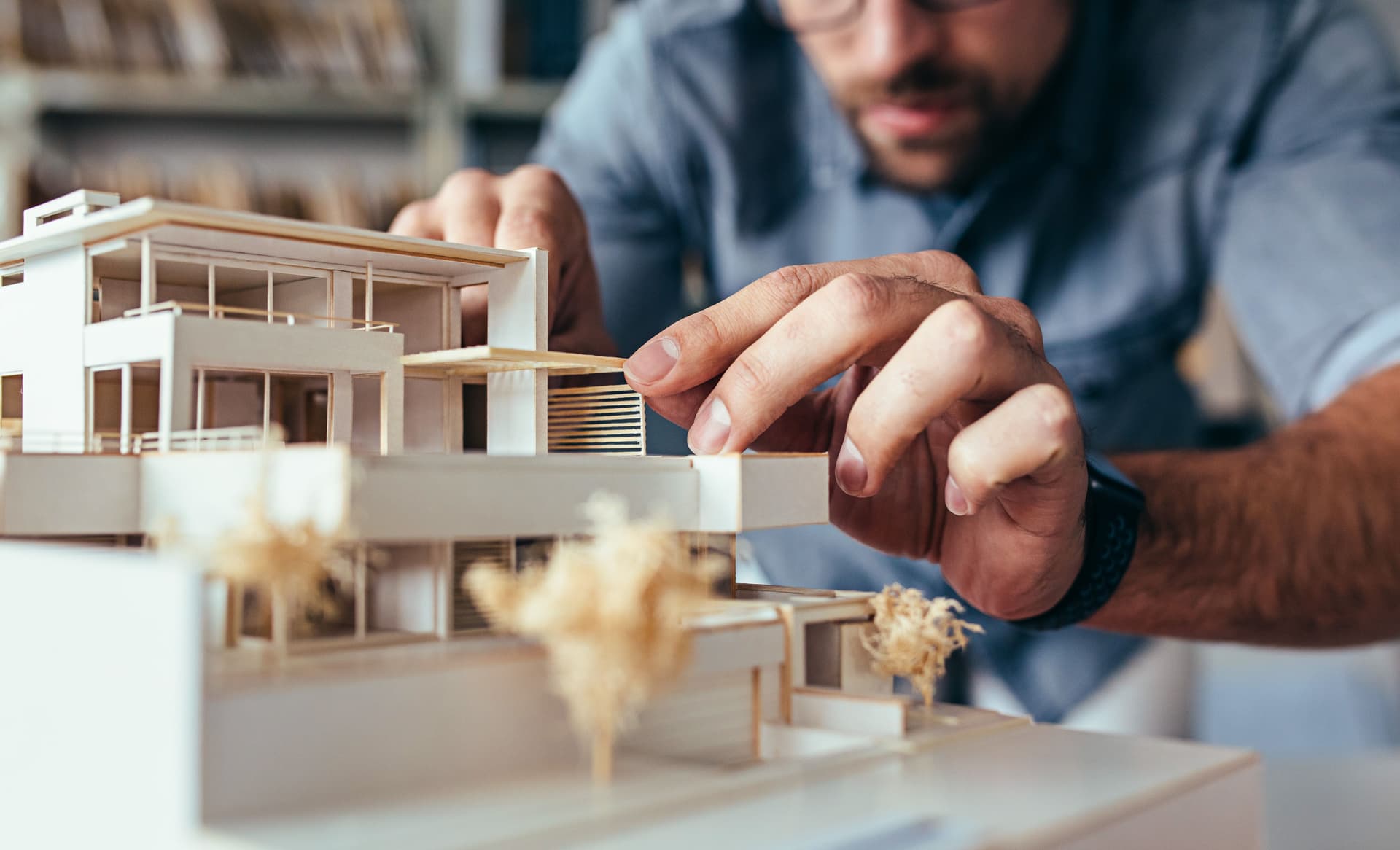 Ein Architekturmodell eines Hauses wird per Hand bearbeitet