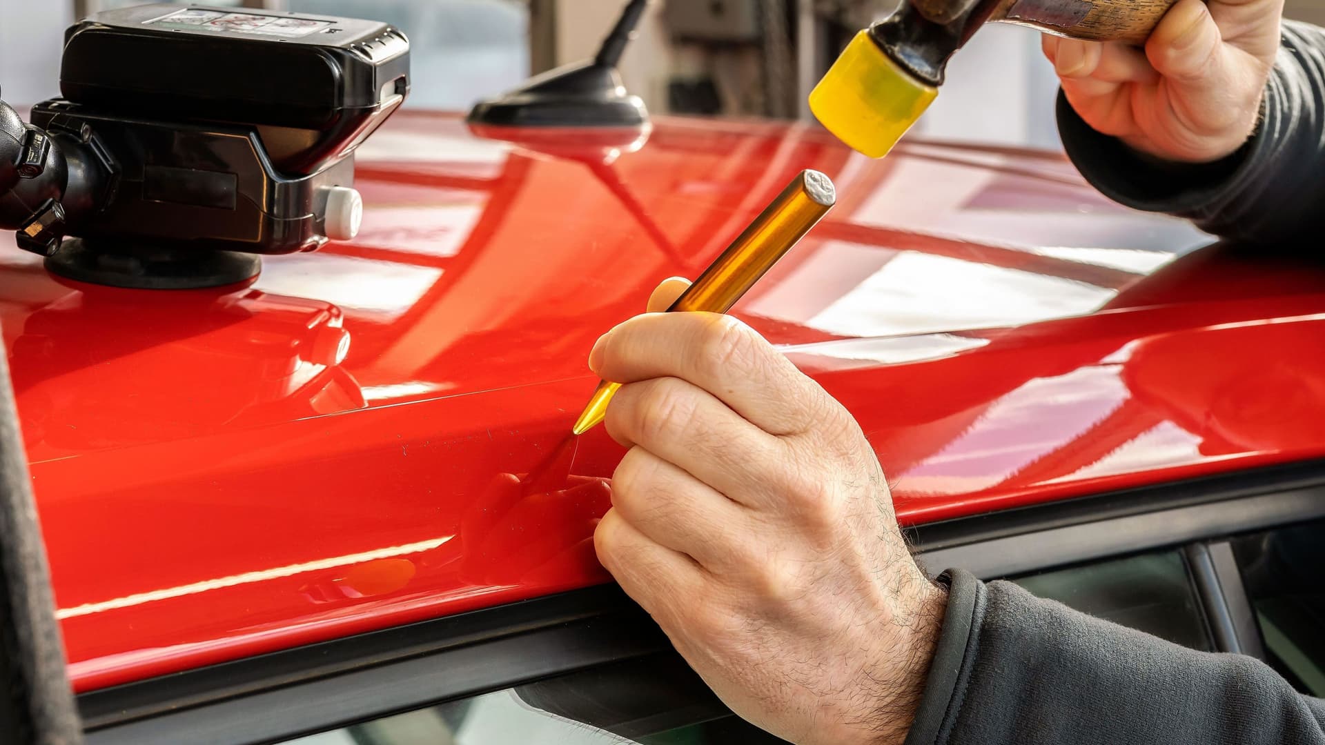 Ein rotes Auto bei der Beulen-Reparatur. 