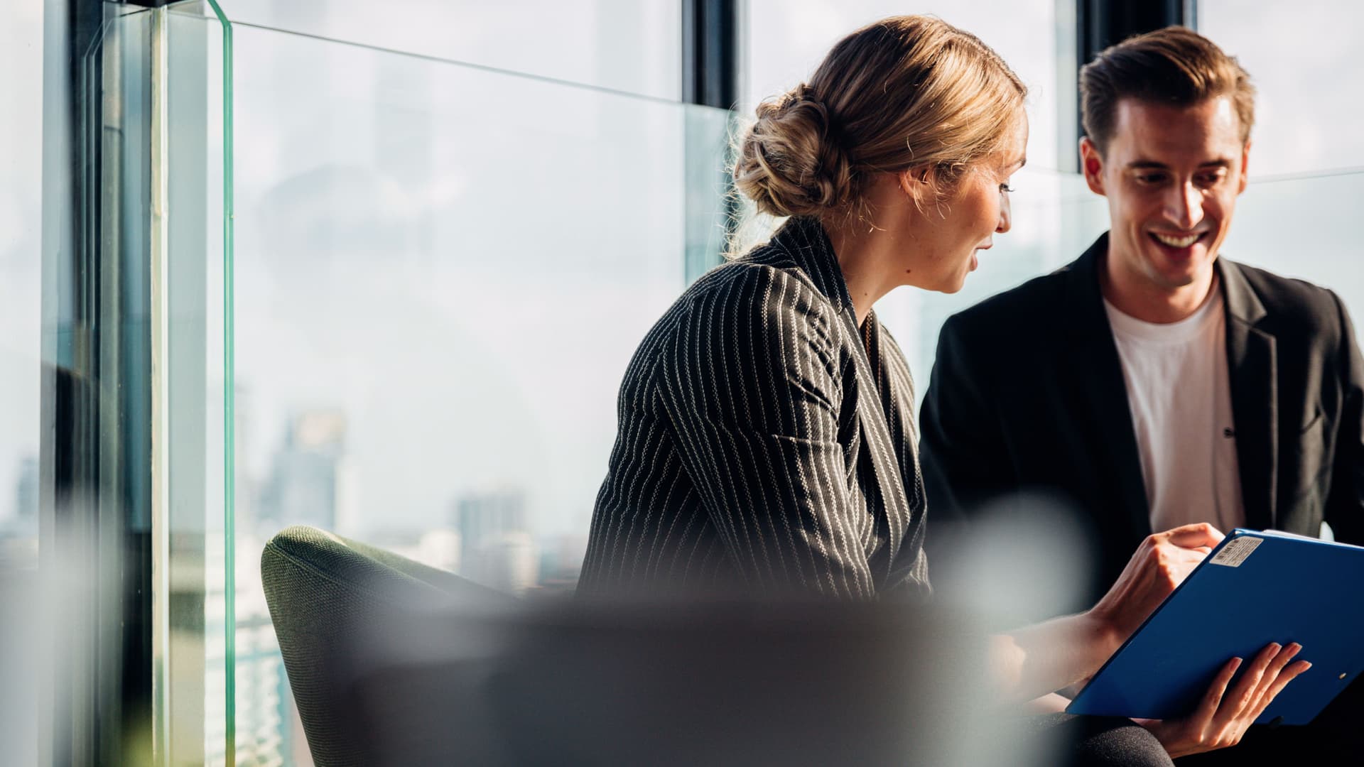 Junge Frau und junger Mann, die zusammen in einem modernen Büro sitzen und etwas besprechen.