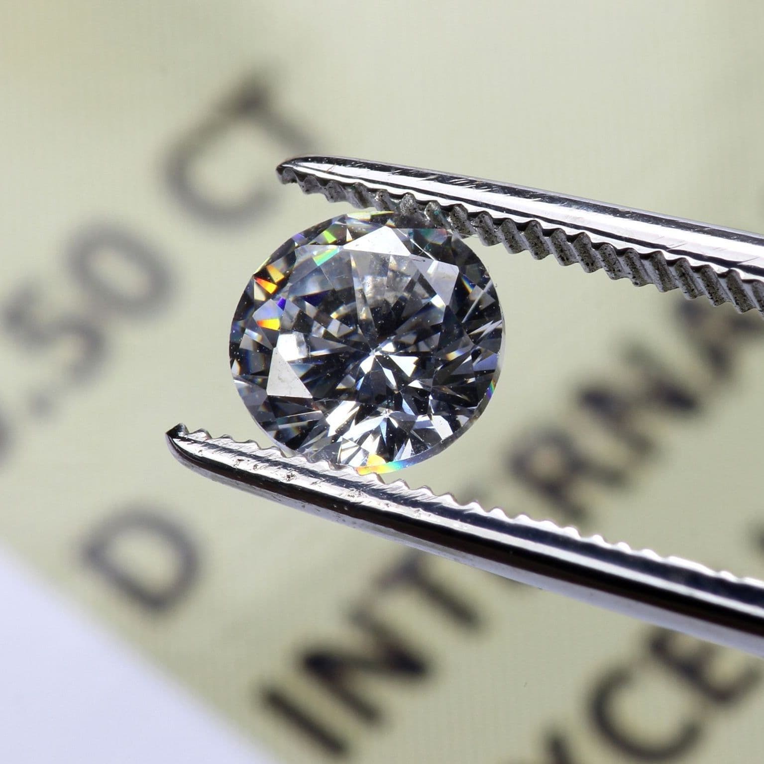 Pinzette hält einen Diamanten. Darunter liegt ein Papier mit Text.