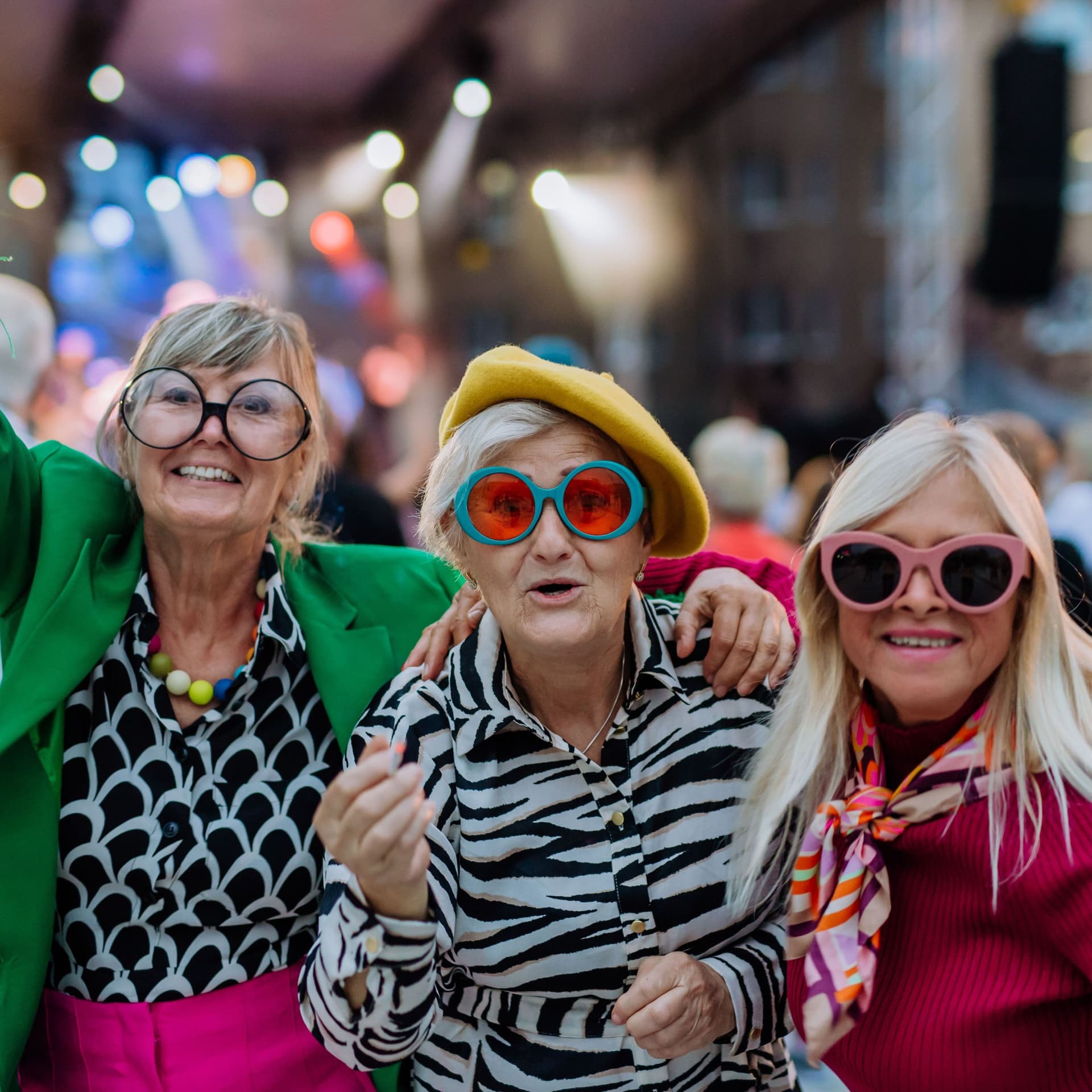 Drei aeltere Ladies feiern auf einem Volksfest. Sie sind bunt gekleidet und haben Spaß.