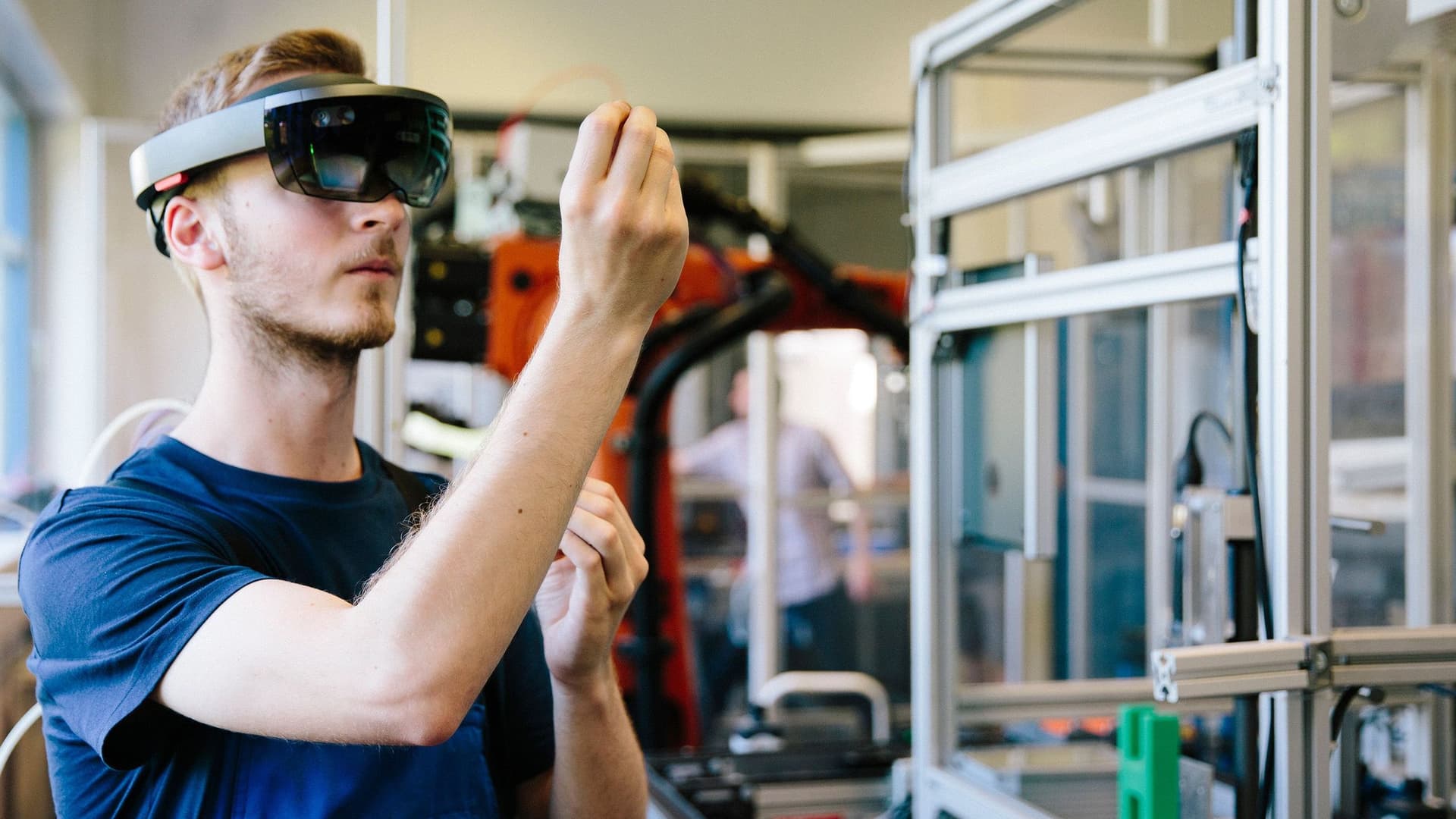 Ein junger Mann mit KI-Brille steht an seiner Arbeitsstelle. 