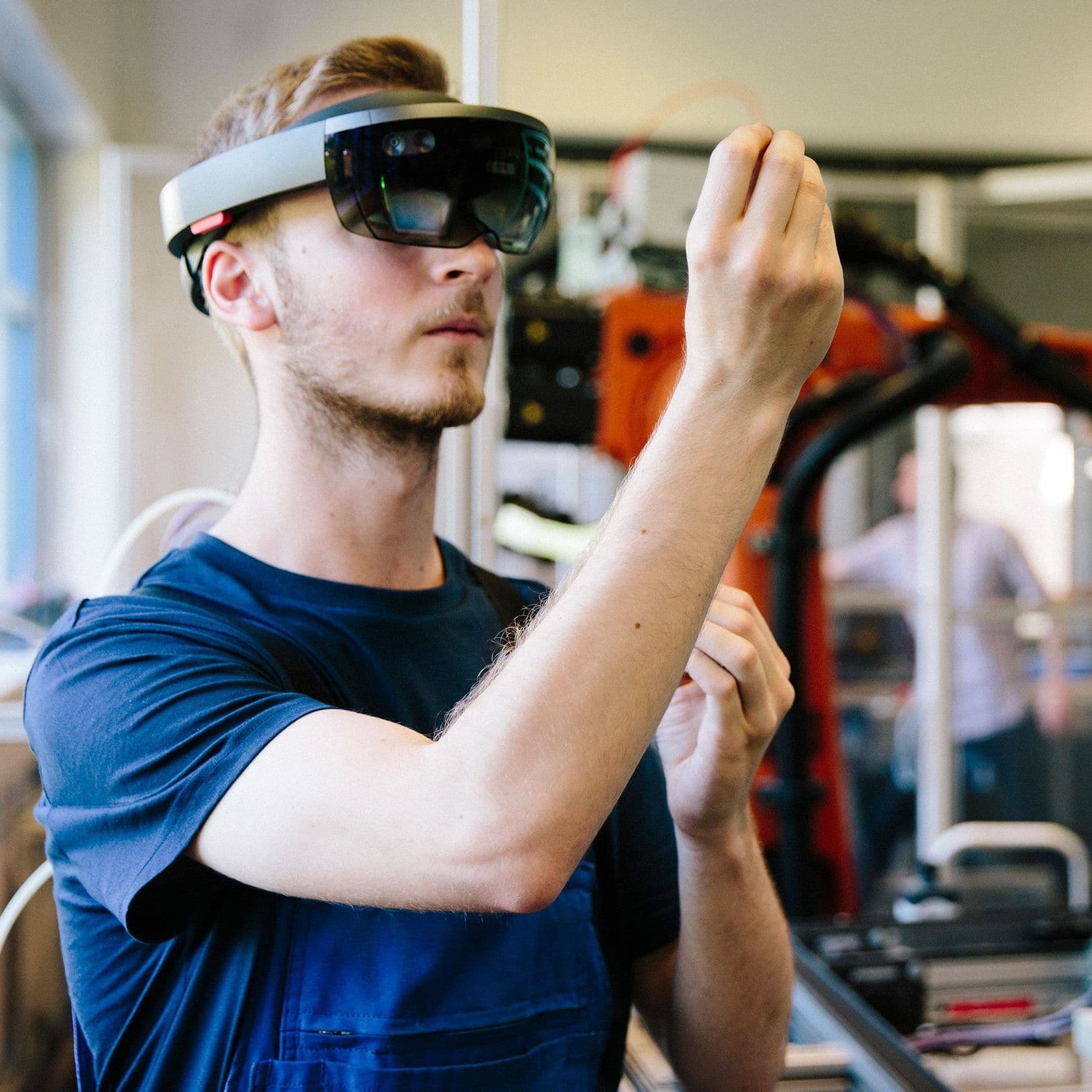 Ein junger Mann mit KI-Brille steht an seiner Arbeitsstelle. 