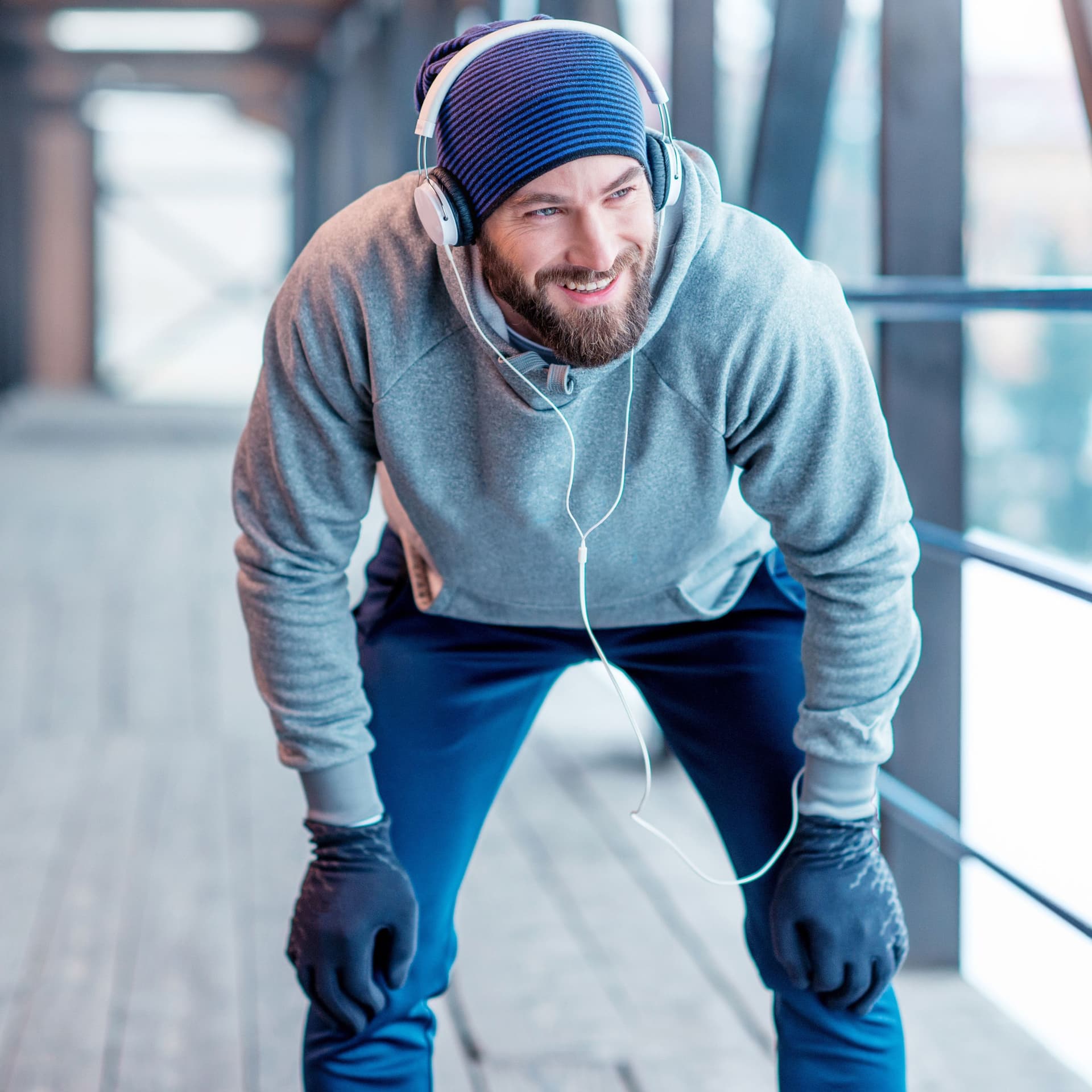 Ein Mann mit Mütze und Handschuhen macht eine Pause vom Joggen.