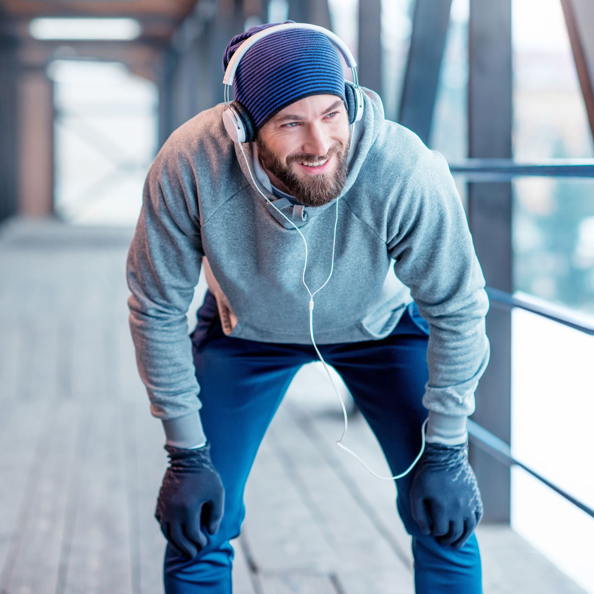 Ein Mann mit Mütze und Handschuhen macht eine Pause vom Joggen.