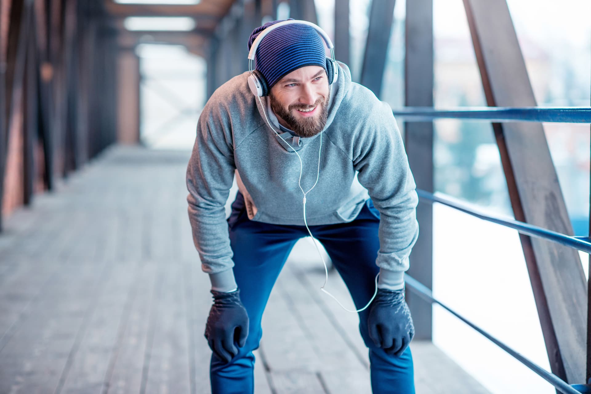 Ein Mann mit Mütze und Handschuhen macht eine Pause vom Joggen.