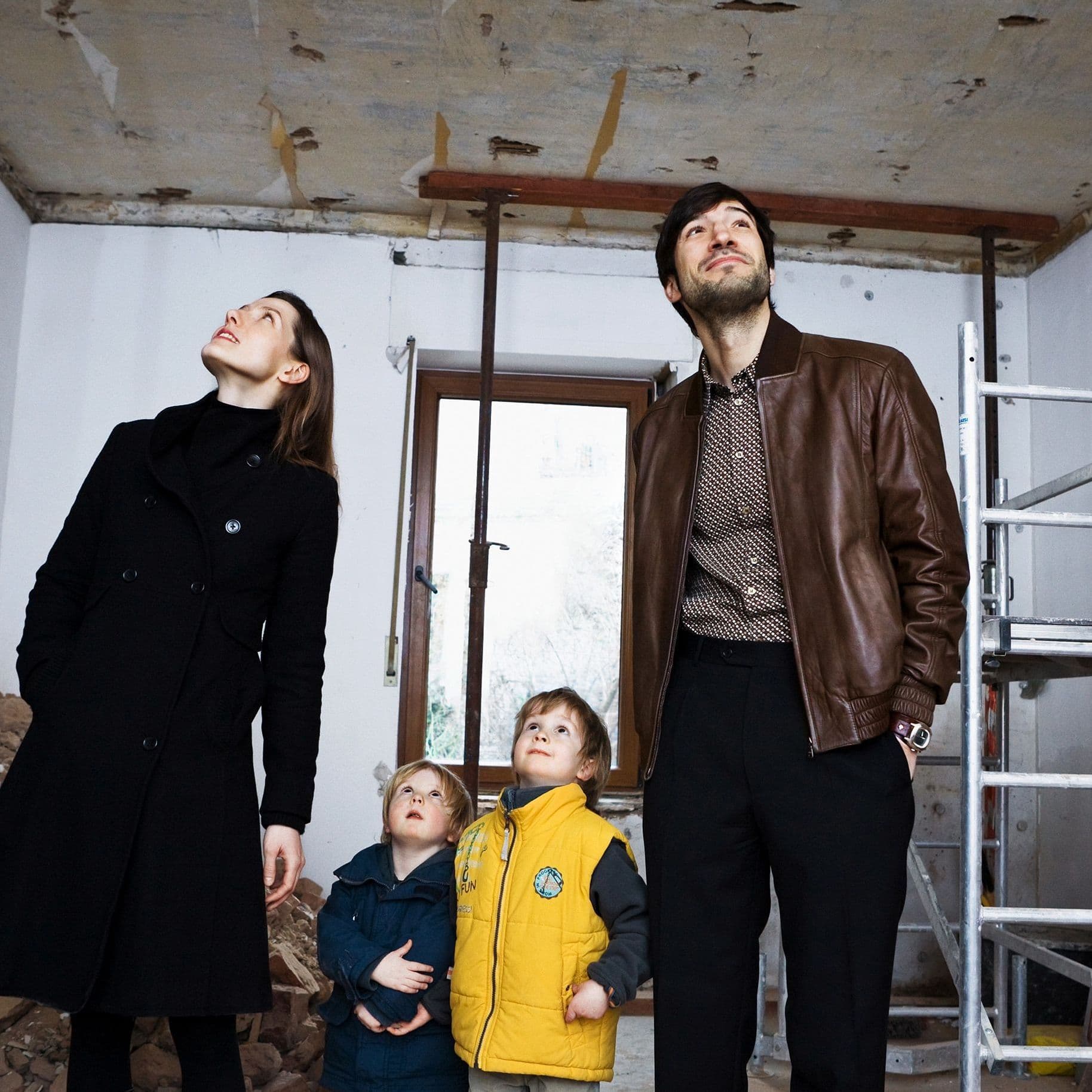 Eine Familie steht in einem sanierungsbedürftigen Haus.