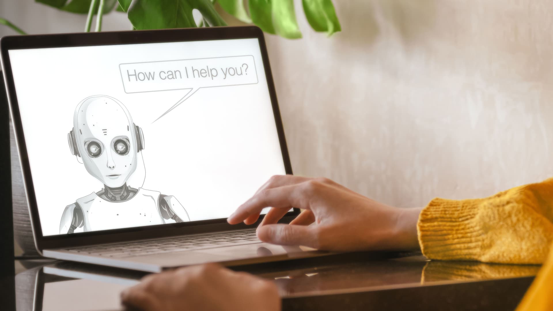 Hand auf einem aufgeklappten Laptop, auf dem Bildschirm ist ein gezeichneter Roboter, der mit der Person redet.