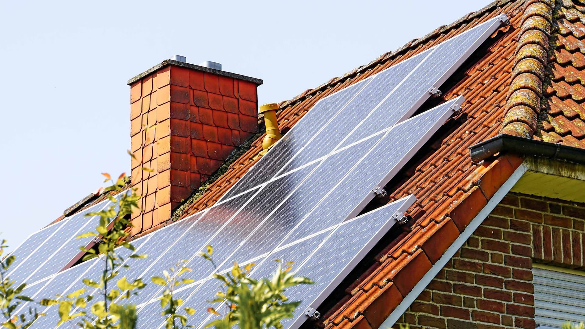 Von einem Einfamilienhaus ist nur das Dach und ein Schornstein zu sehen. Auf der Dachschräge sind eine Vielzahl von Solarpannels zu sehen.
