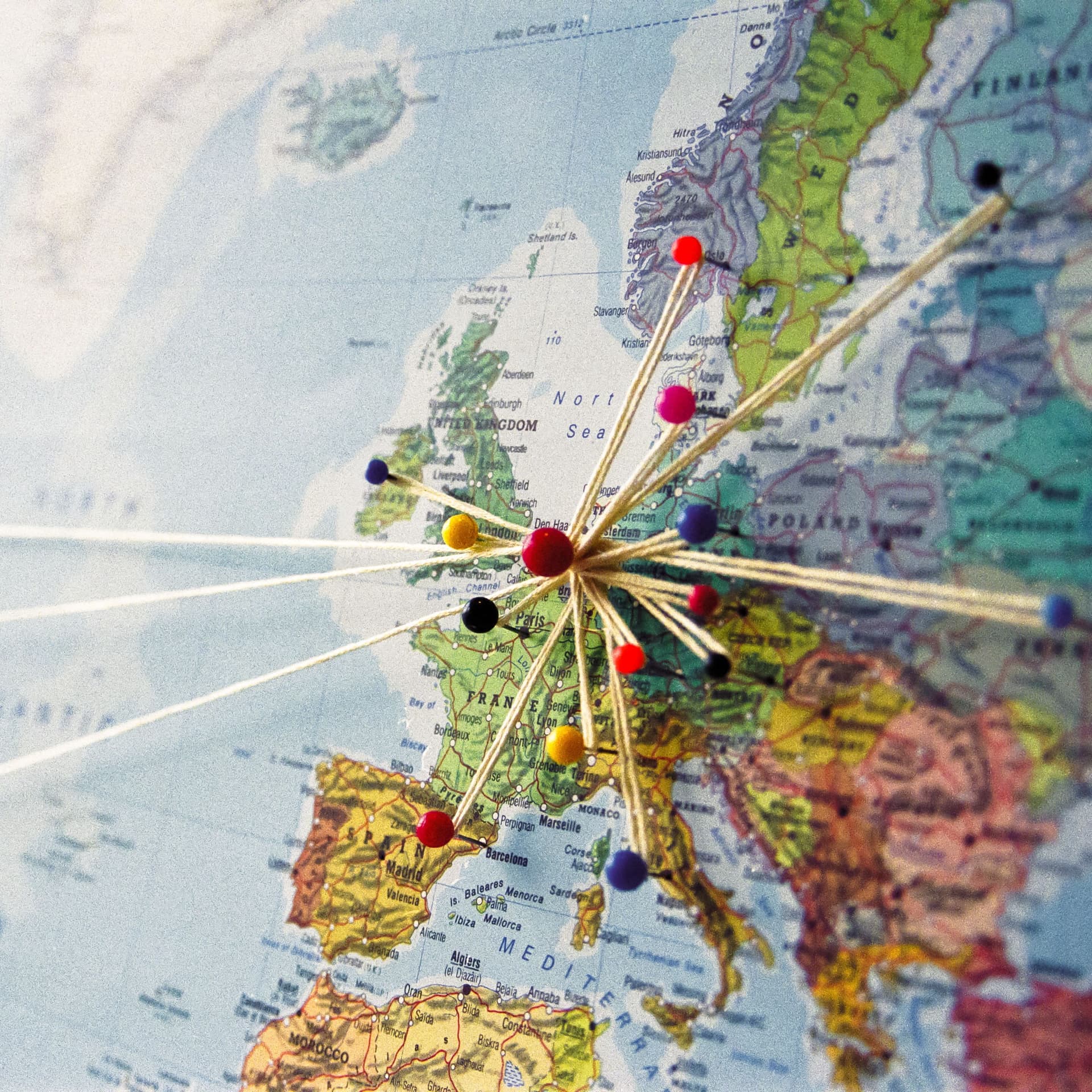 Karte von Europa und der Ostküste der U.S.A. mit Stecknadeln und Fäden versehen. Zentrum der Fäden ist Europa.