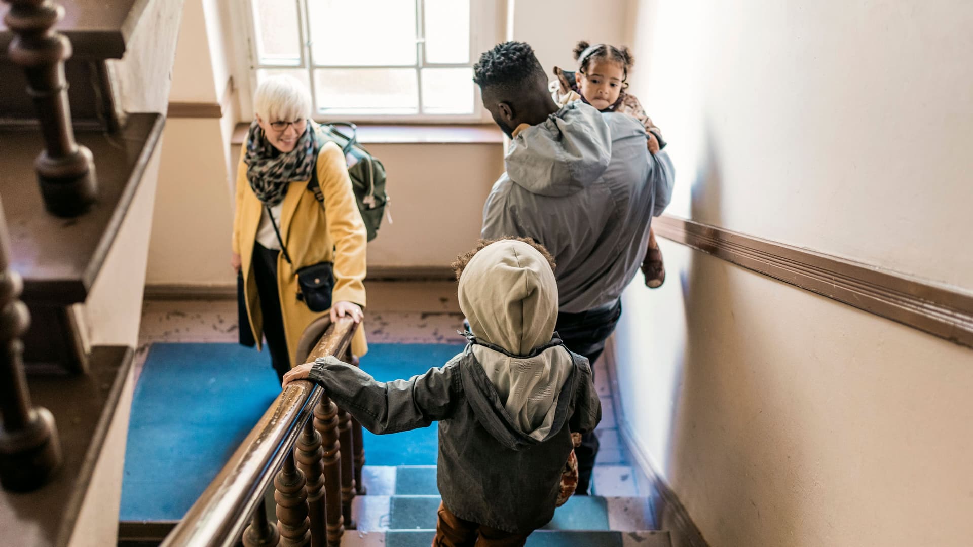 Eine Familie, die gemeinsam eine Treppe hinuntergeht, um das Haus zu verlassen.