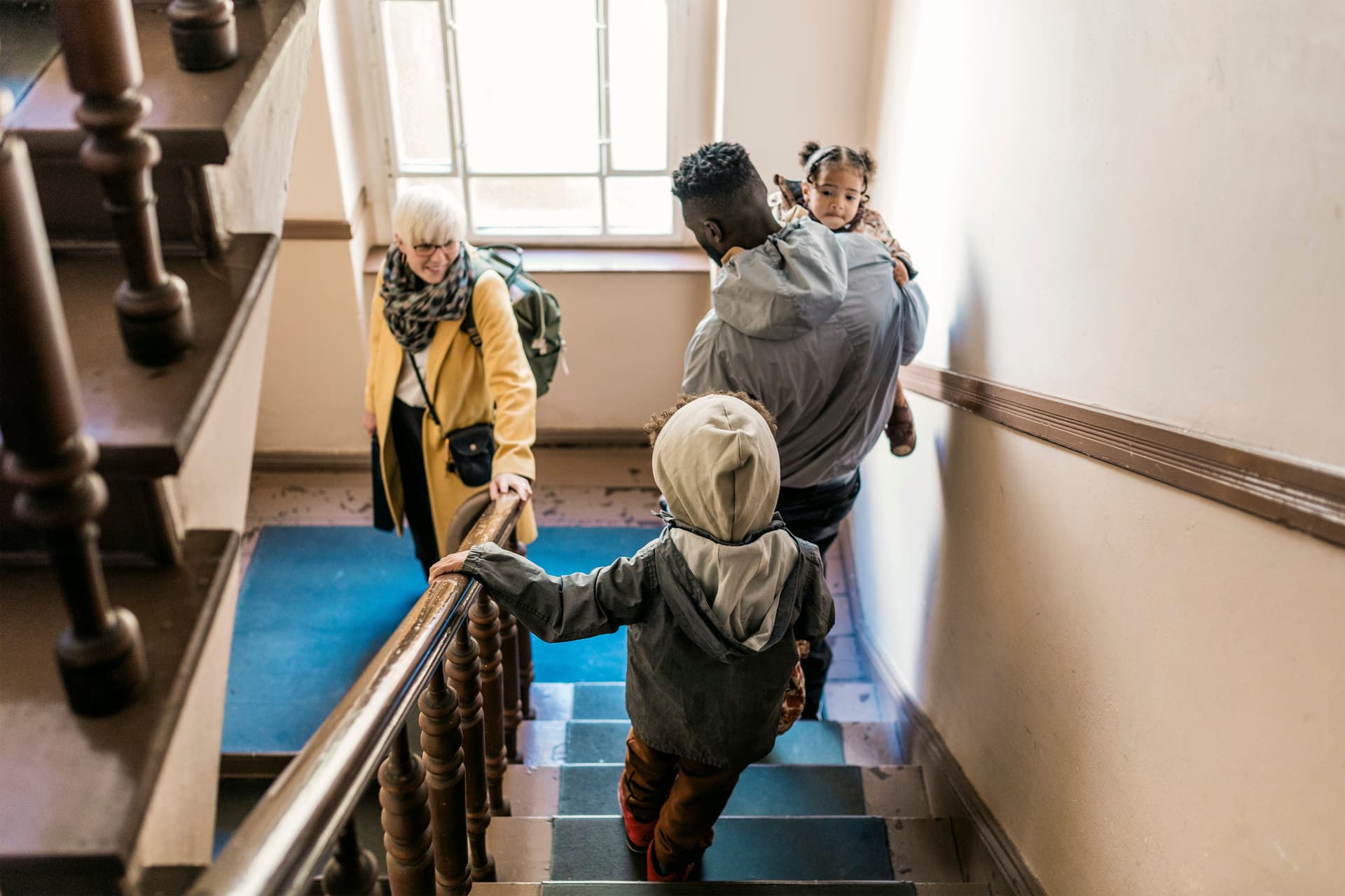 Eine Familie, die gemeinsam eine Treppe hinuntergeht, um das Haus zu verlassen.