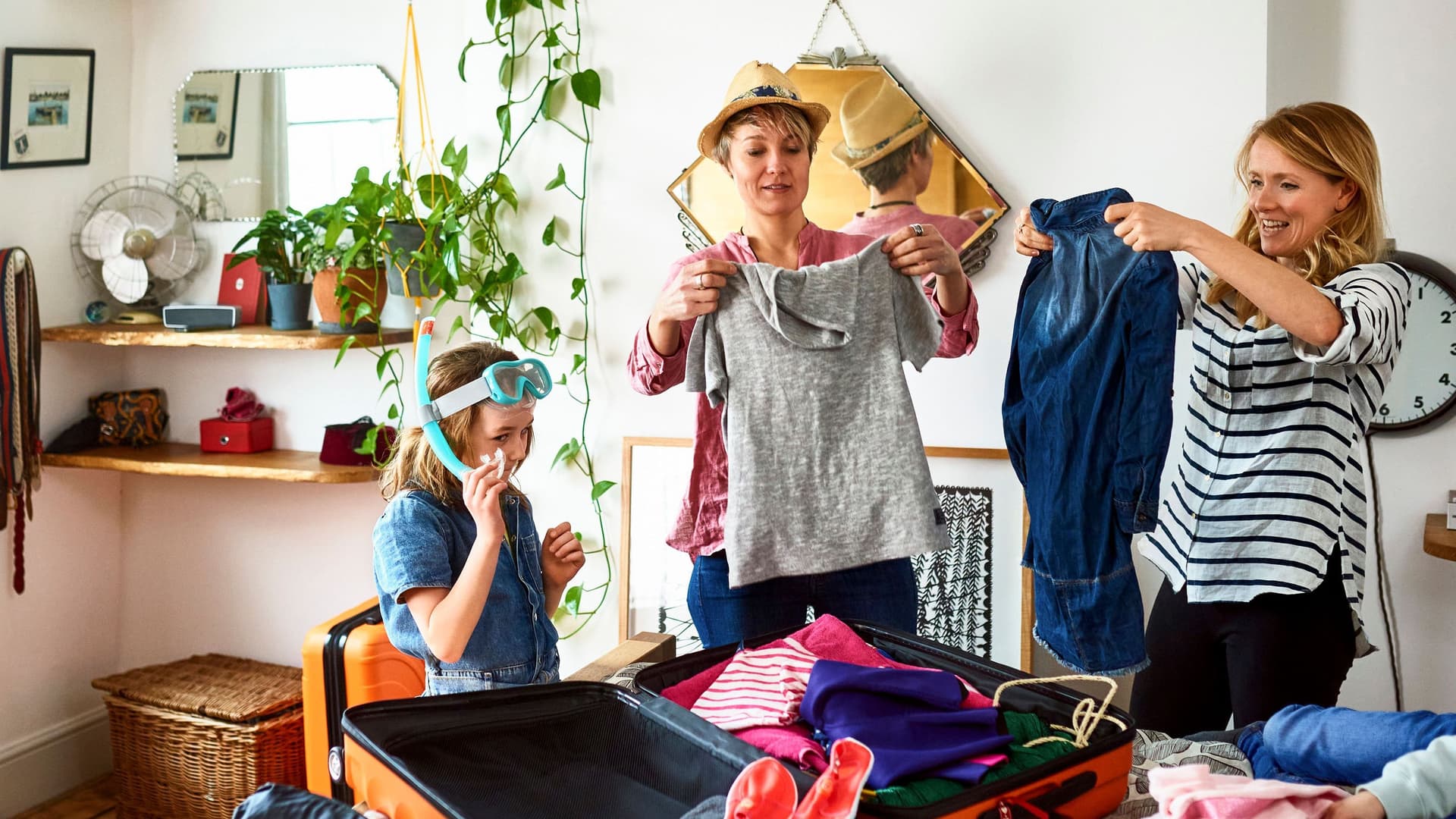 Zwei Frauen packen mit ihren Kindern die Koffer für den Sommerurlaub