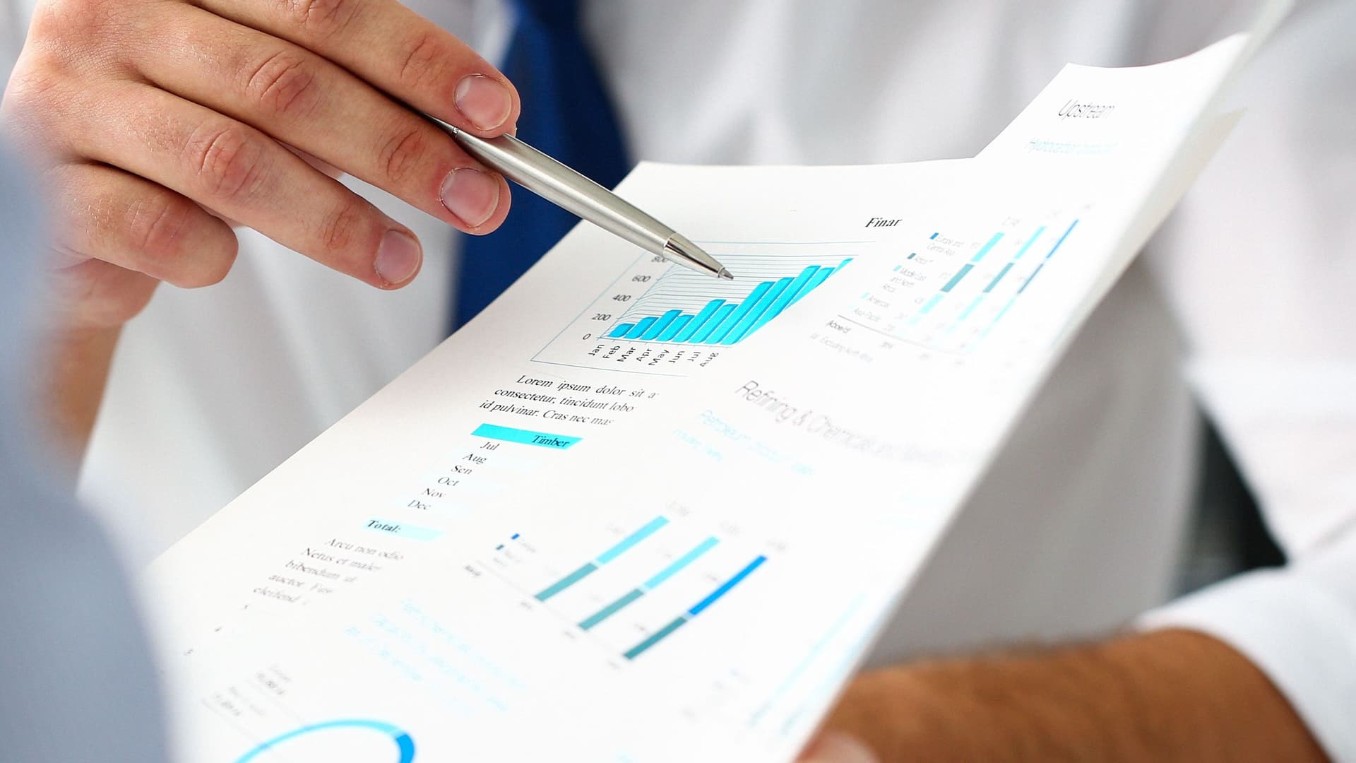 Gruppe von Geschäftsleuten mit Finanzdiagramm und silbernem Stift diskutieren.