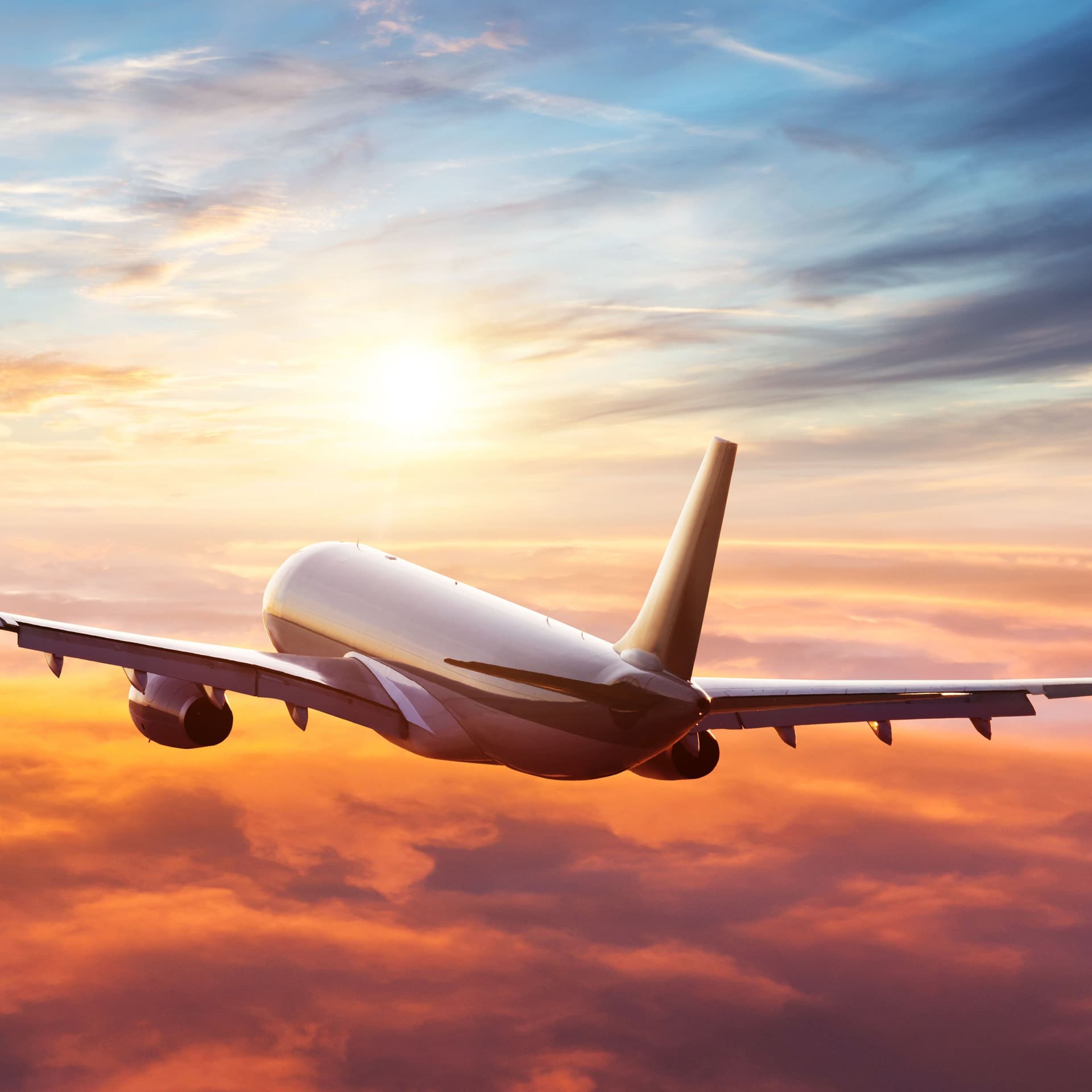 Flugzeug fliegt über den Wolken Richtung Sonnenuntergang