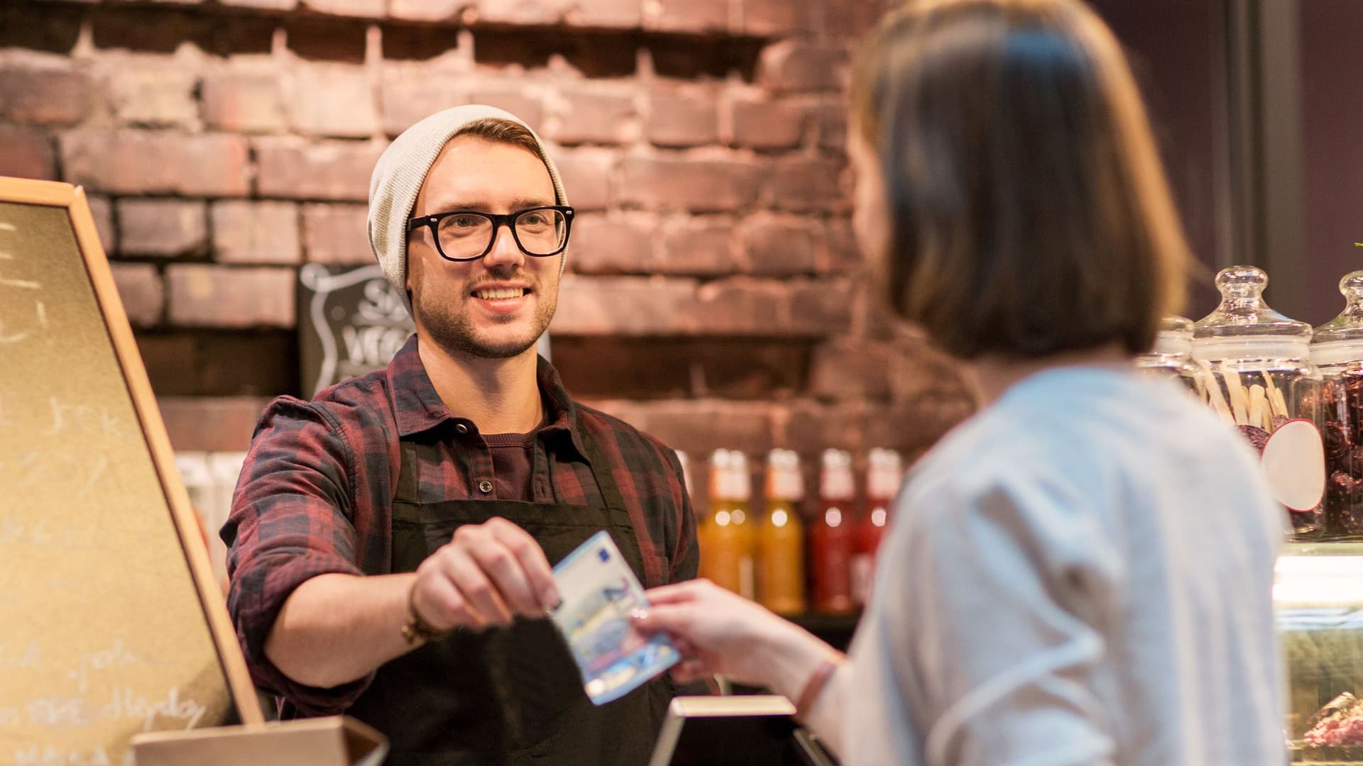 Kundin zahlt bar an Tresen eines Restaurants.