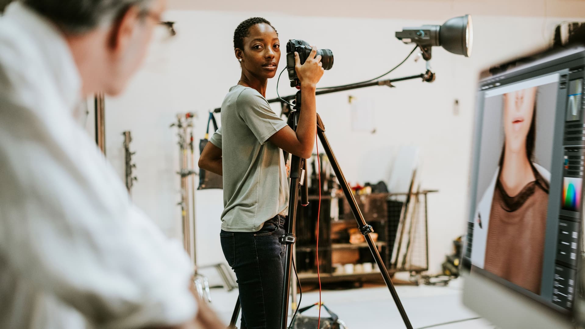 Im Fotostudio steht ein Mann vor dem Computer und bespricht eine Aufnahme mit der Fotografin, die hinter der Kamera steht.