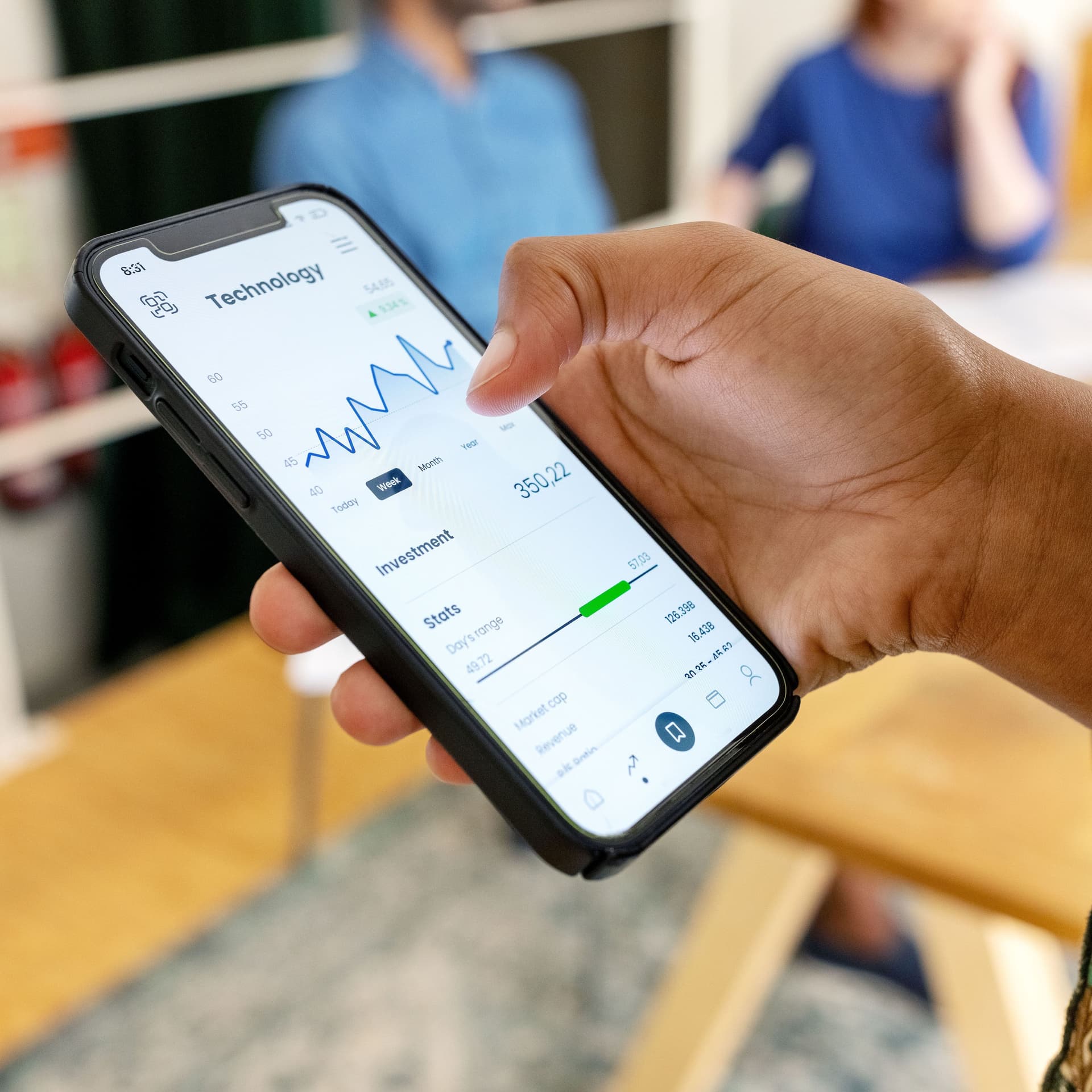 Eine Frau hat ein Handy in der Hand mit einer Trading-App.