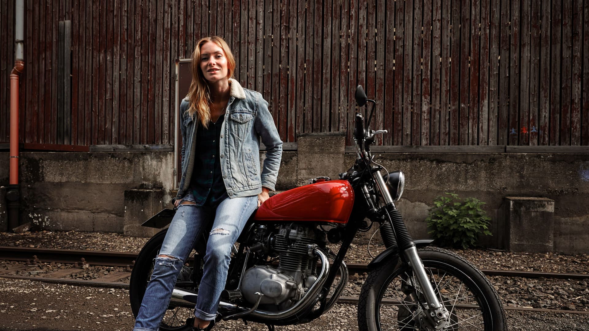 Eine junge Frau sitzt auf einem stehenden Motorrad.
