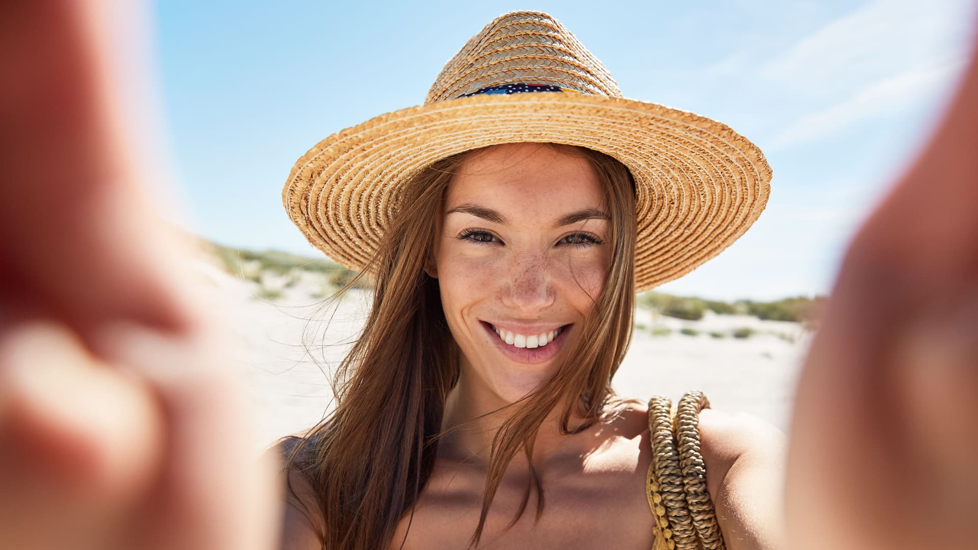 Junge Frau macht ein Selfie am Strand.
