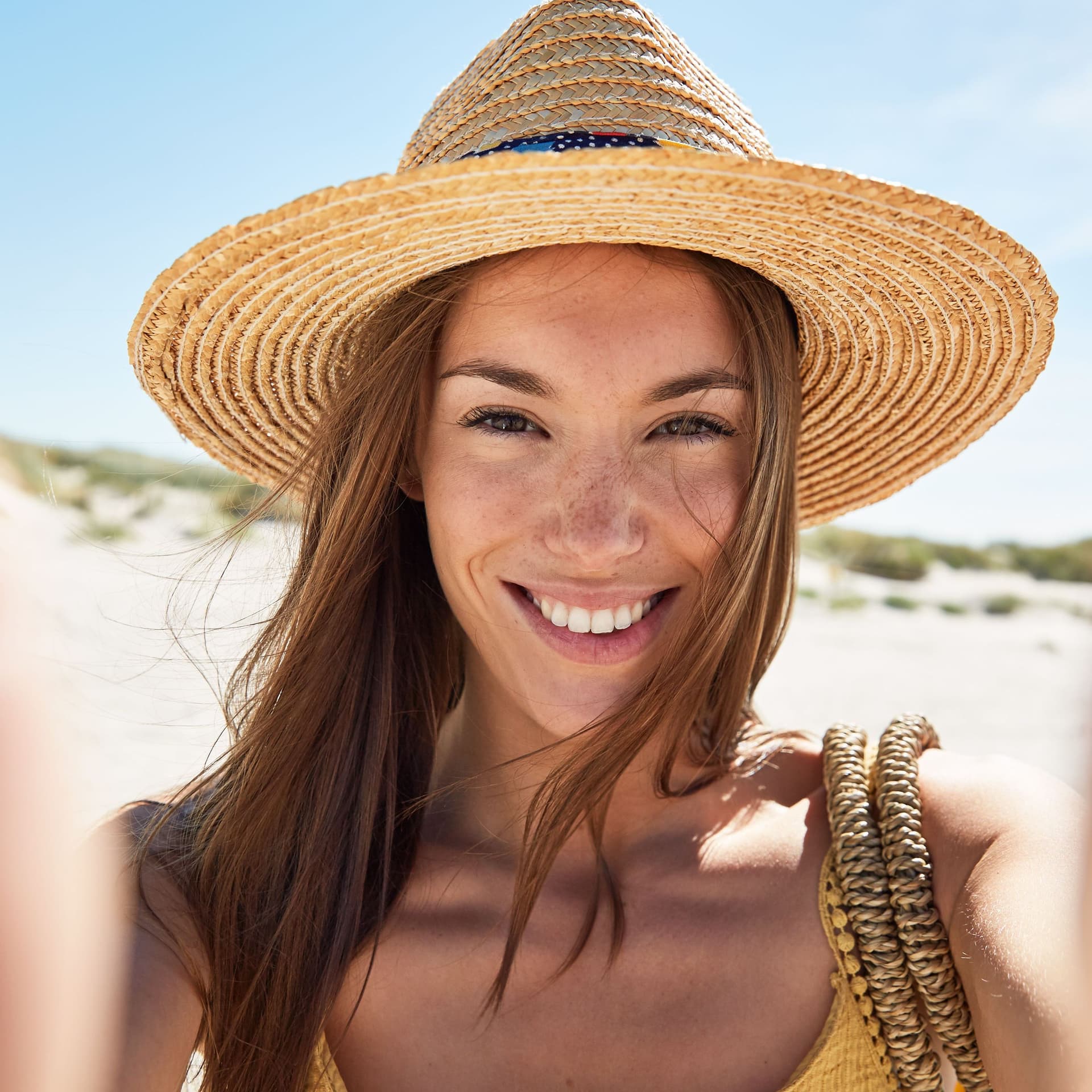 Junge Frau macht ein Selfie am Strand.