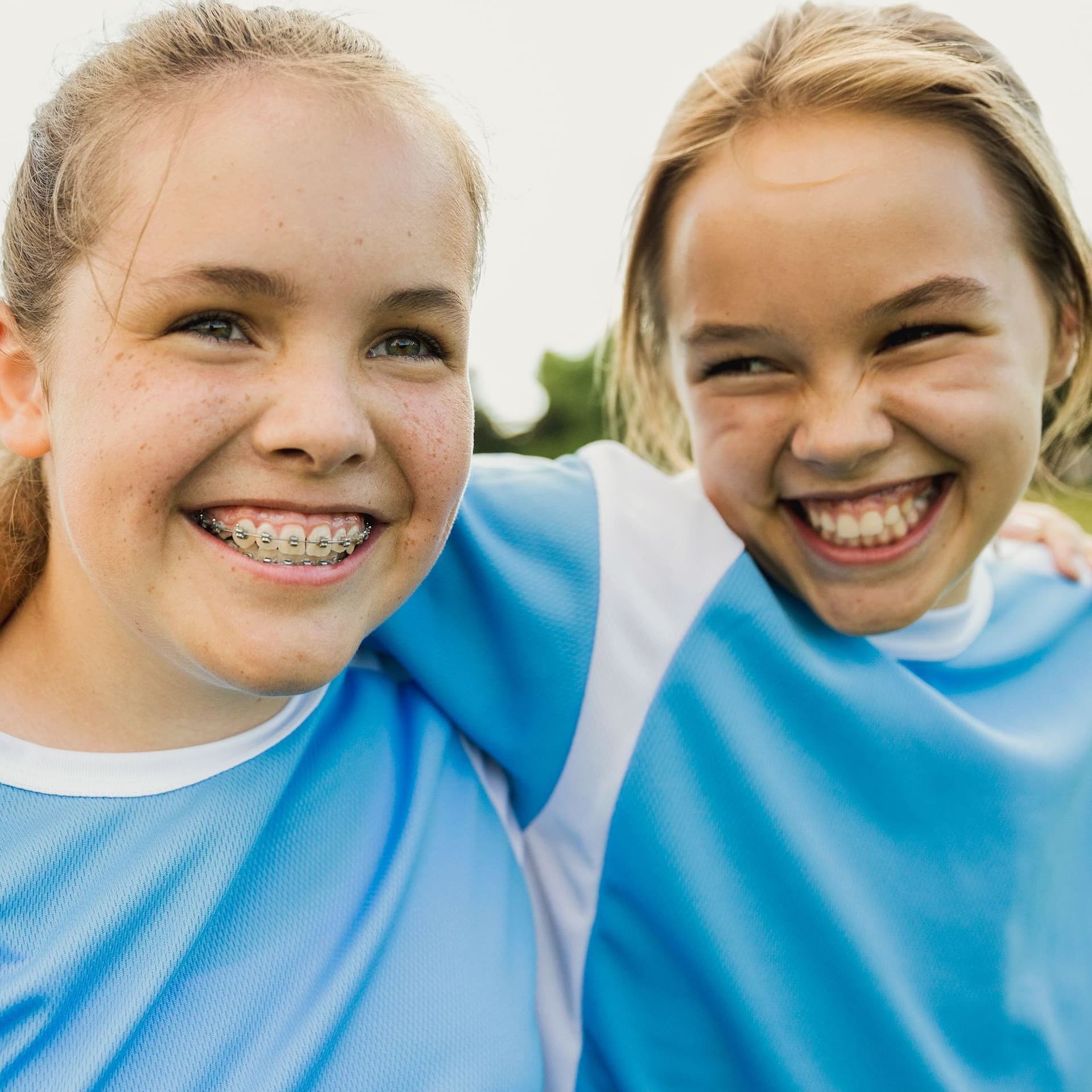 Fröhliche Teenagerinnen umarmen sich auf dem Fußballplatz