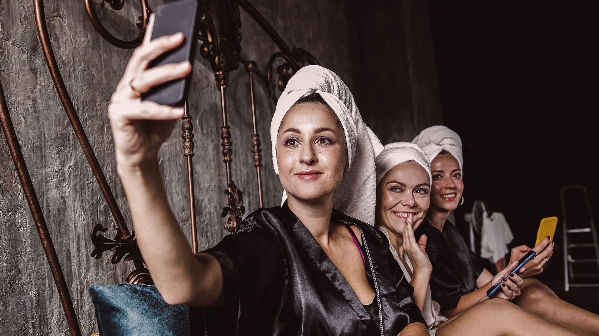 Drei Frauen in Bademänteln und Handtüchern auf dem Kopf machen ein Selfie