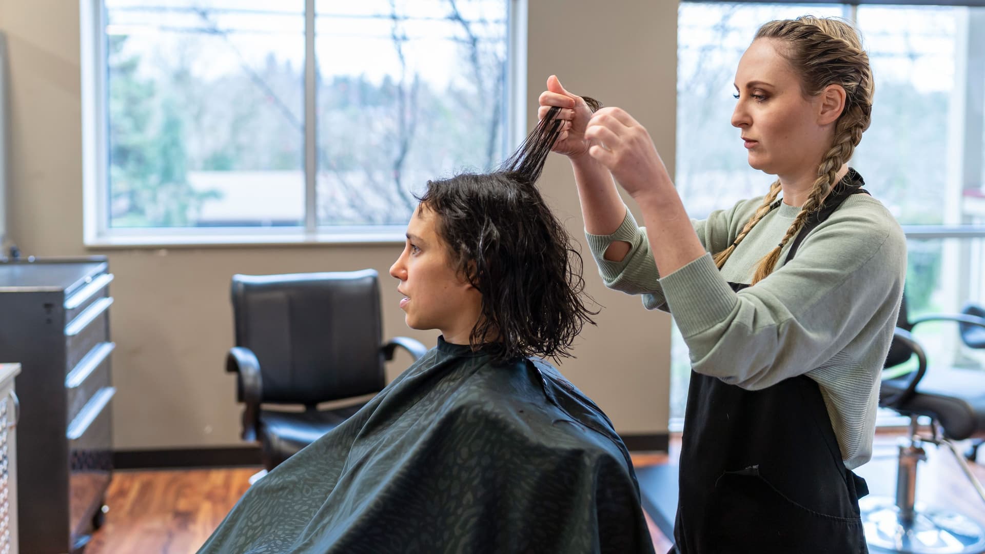 Eine Friseurin frisiert einen Kundin die Haare. 