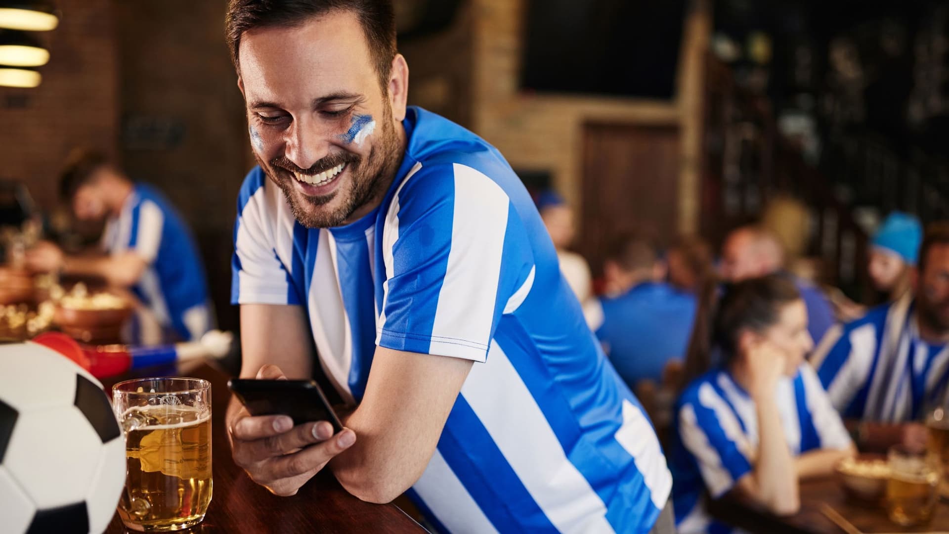 Bezahlgewohnheiten Fußballfan mit Handy in der Kneipe