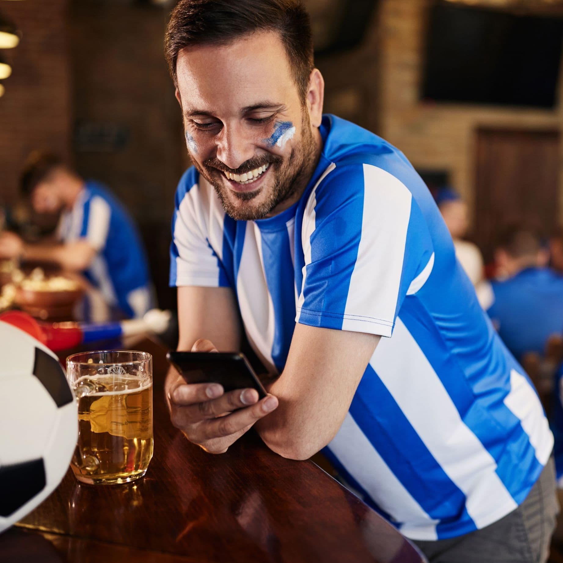 Bezahlgewohnheiten Fußballfan mit Handy in der Kneipe