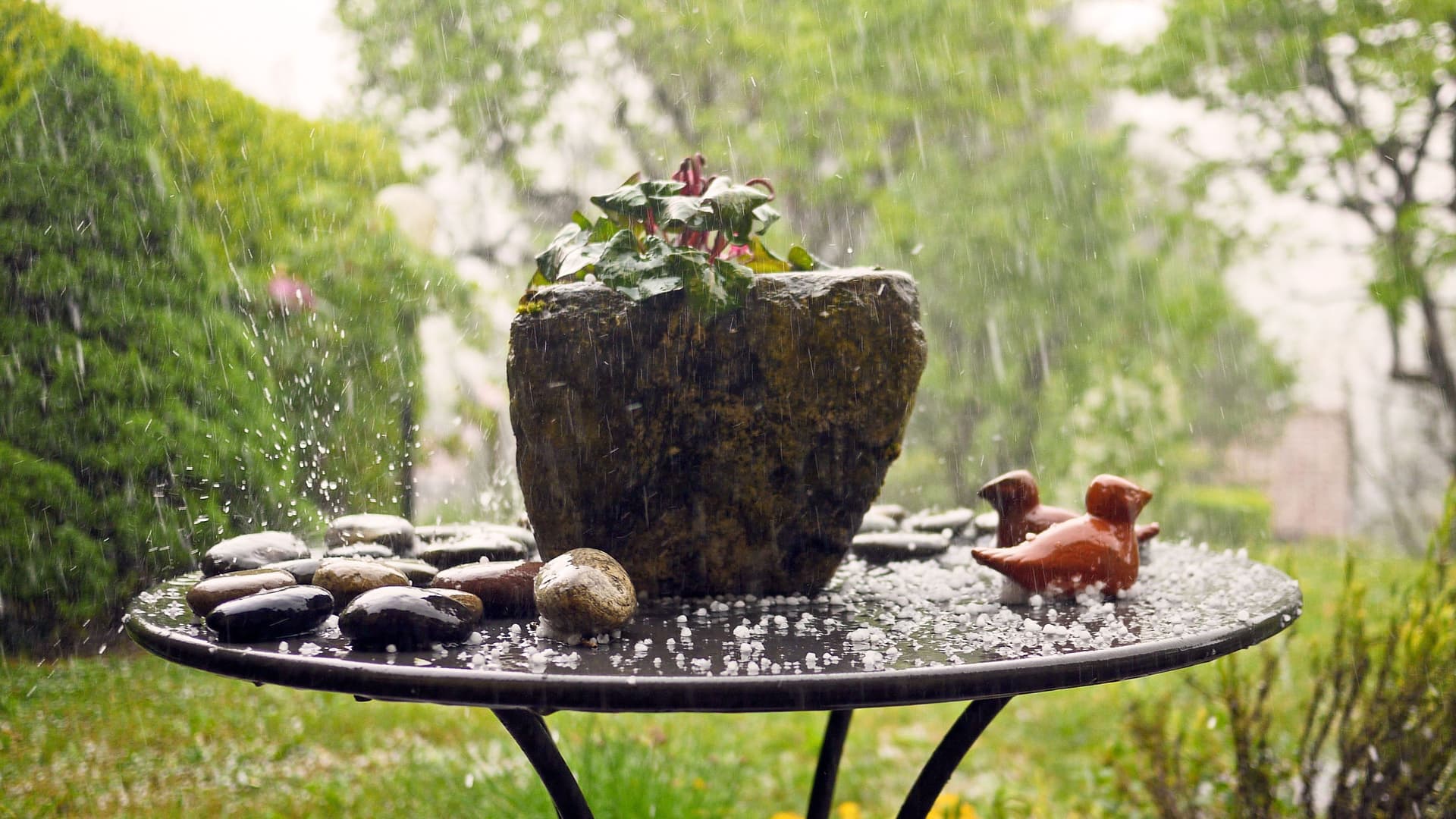 Ein Gartentisch mit Hagelkörnern. Im Hintergrund ein Garten.