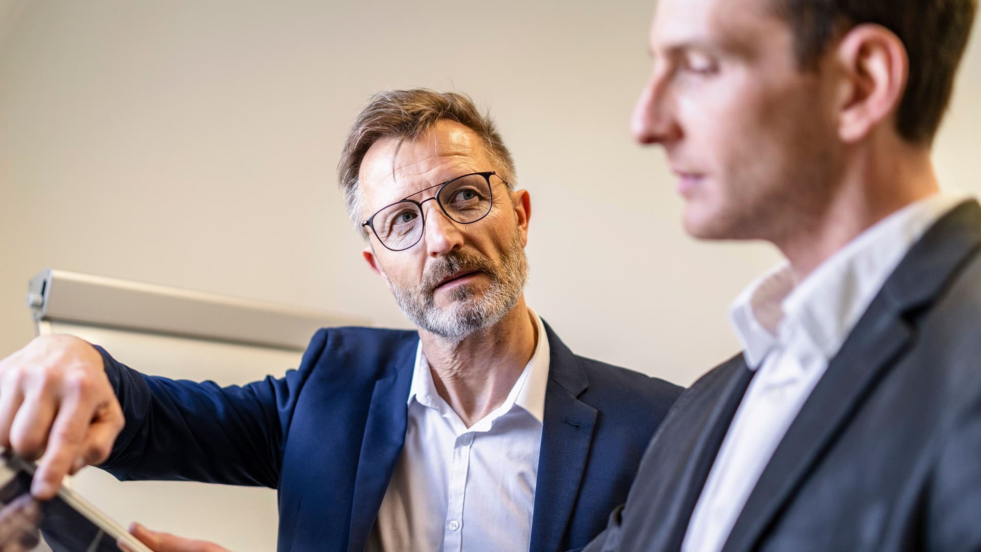 Zwei Geschäftsmänner im Büro diskutieren. Sie haben eine Solarzelle vor sich.