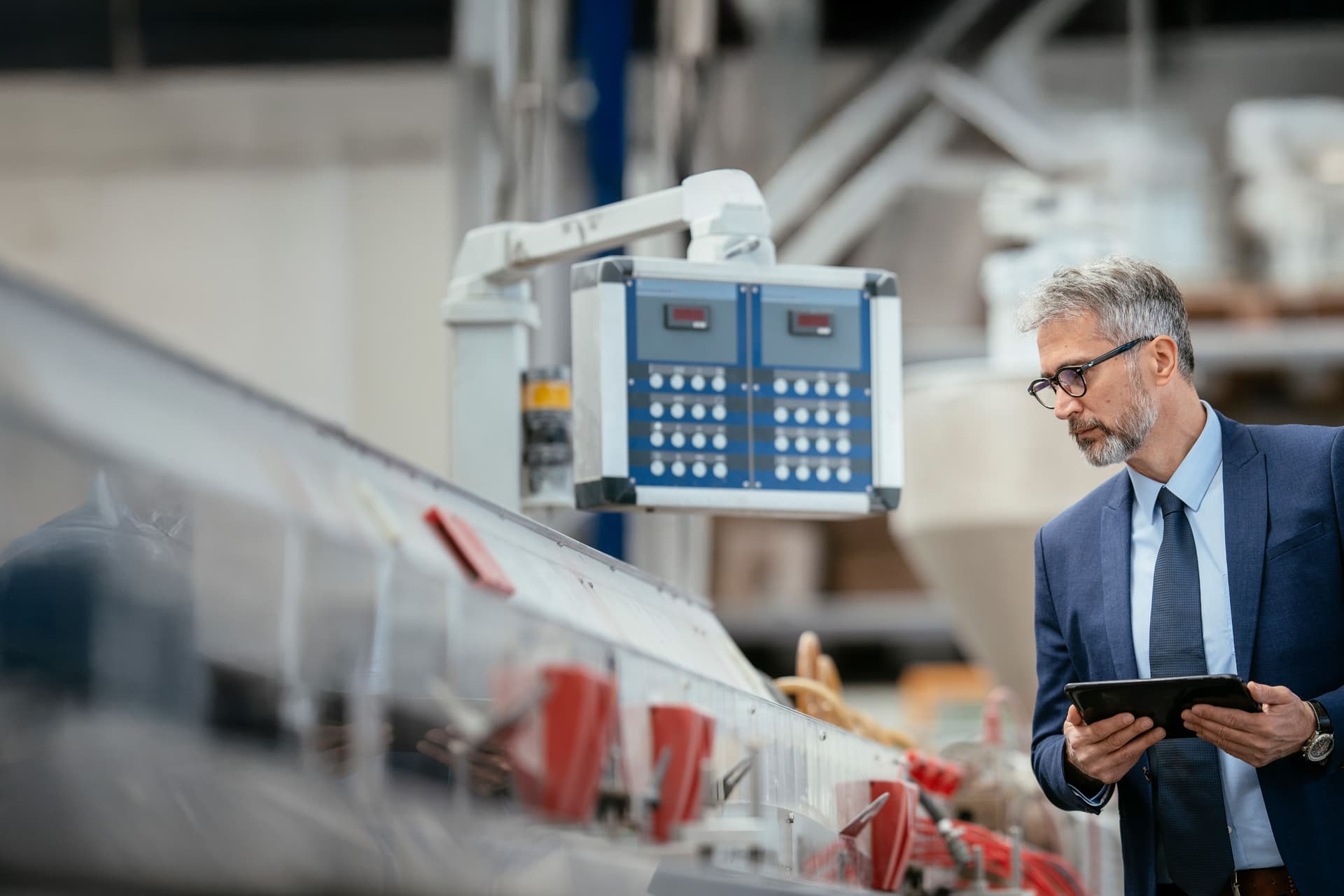 Mittelalter Ingenieur in einer Produktionshalle. Er hat eine Mappe in den Händen und prüft etwas.