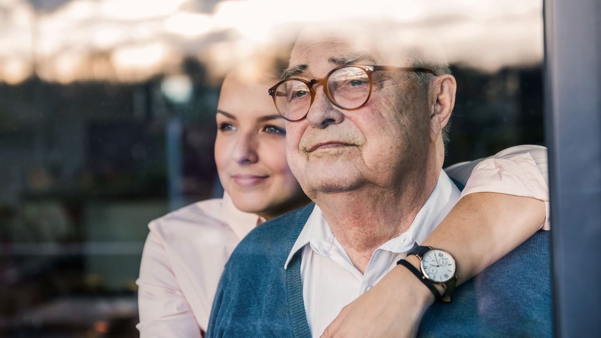 Porträt einer jungen Frau, die einen älteren Mann am Fenster umarmt