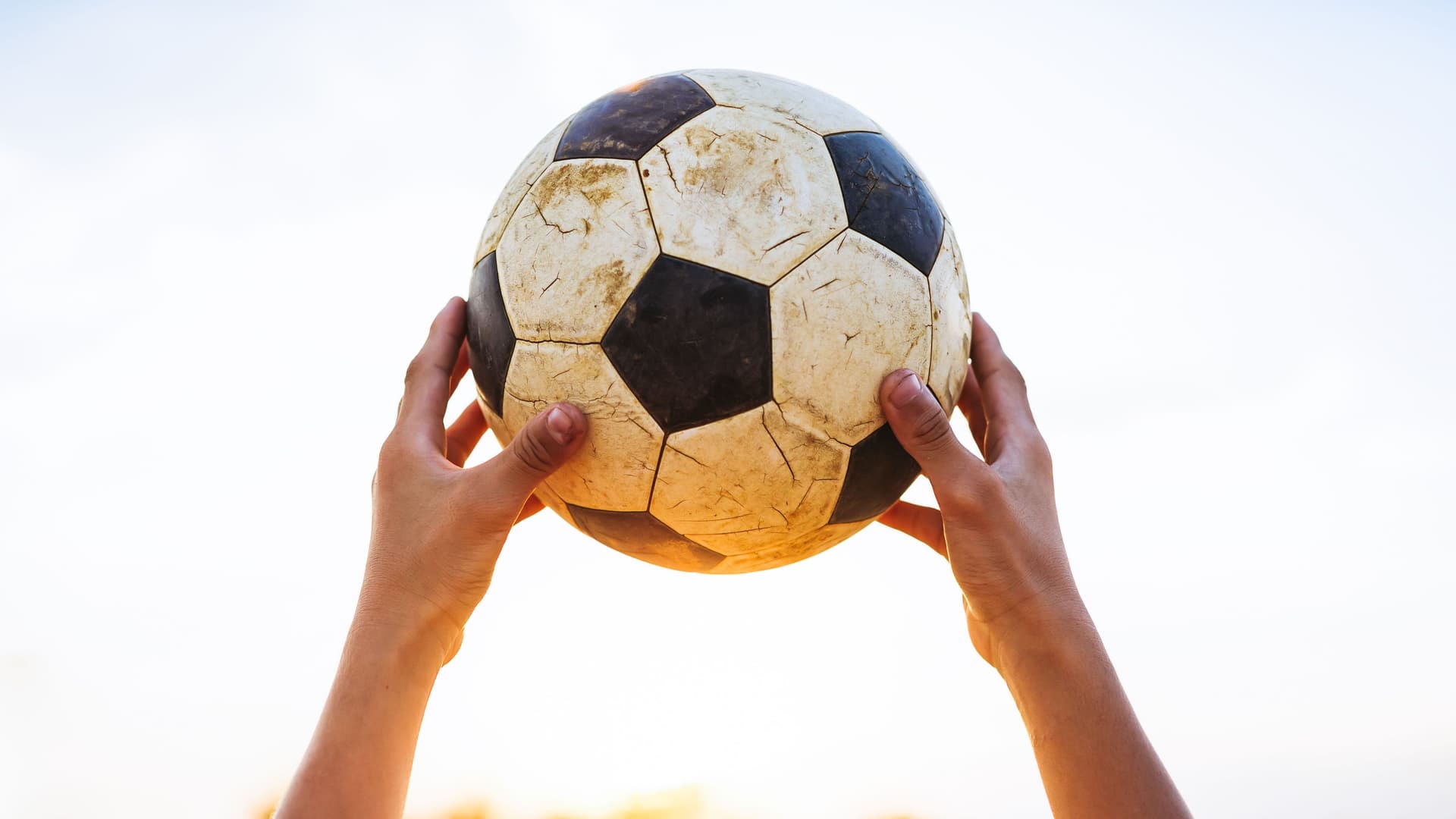 Hände halten einen alten Fußball hoch